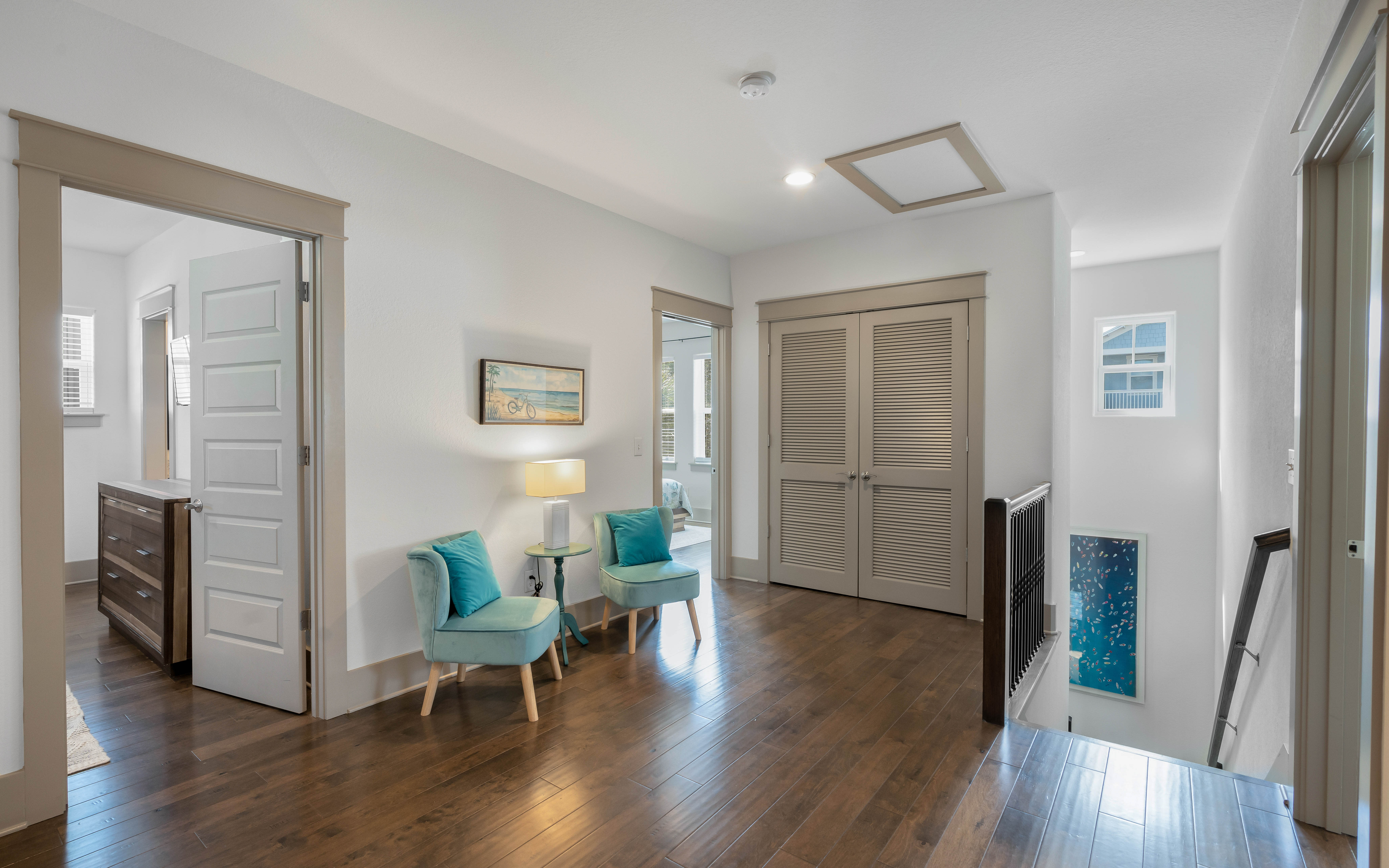 Relax in this elegant upstairs landing with cozy turquoise seating and warm hardwood floors throughout.