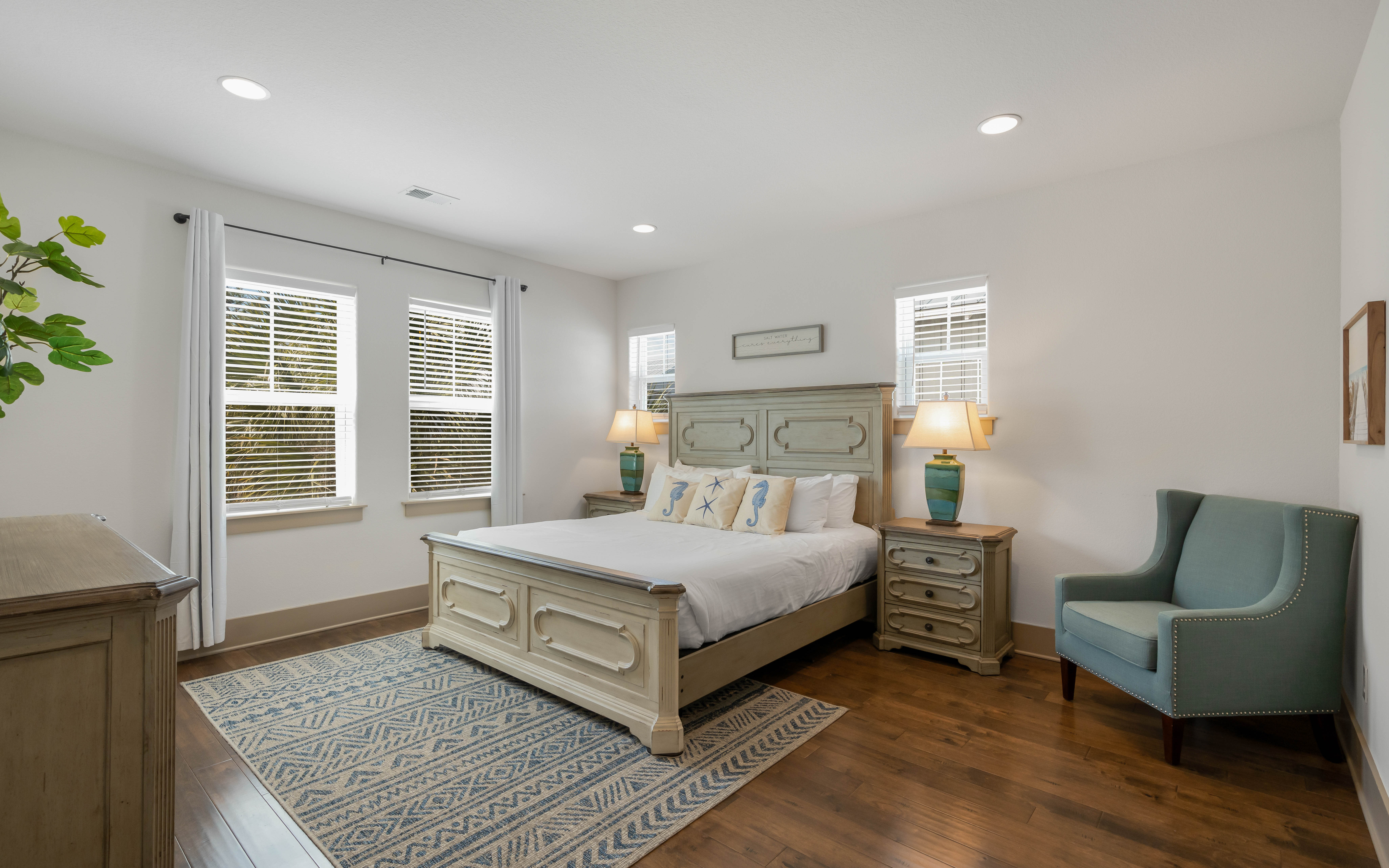 Sink into your elegant bedroom retreat featuring coastal-inspired furnishings, soft linens, and natural light filtering through plantation shutters.