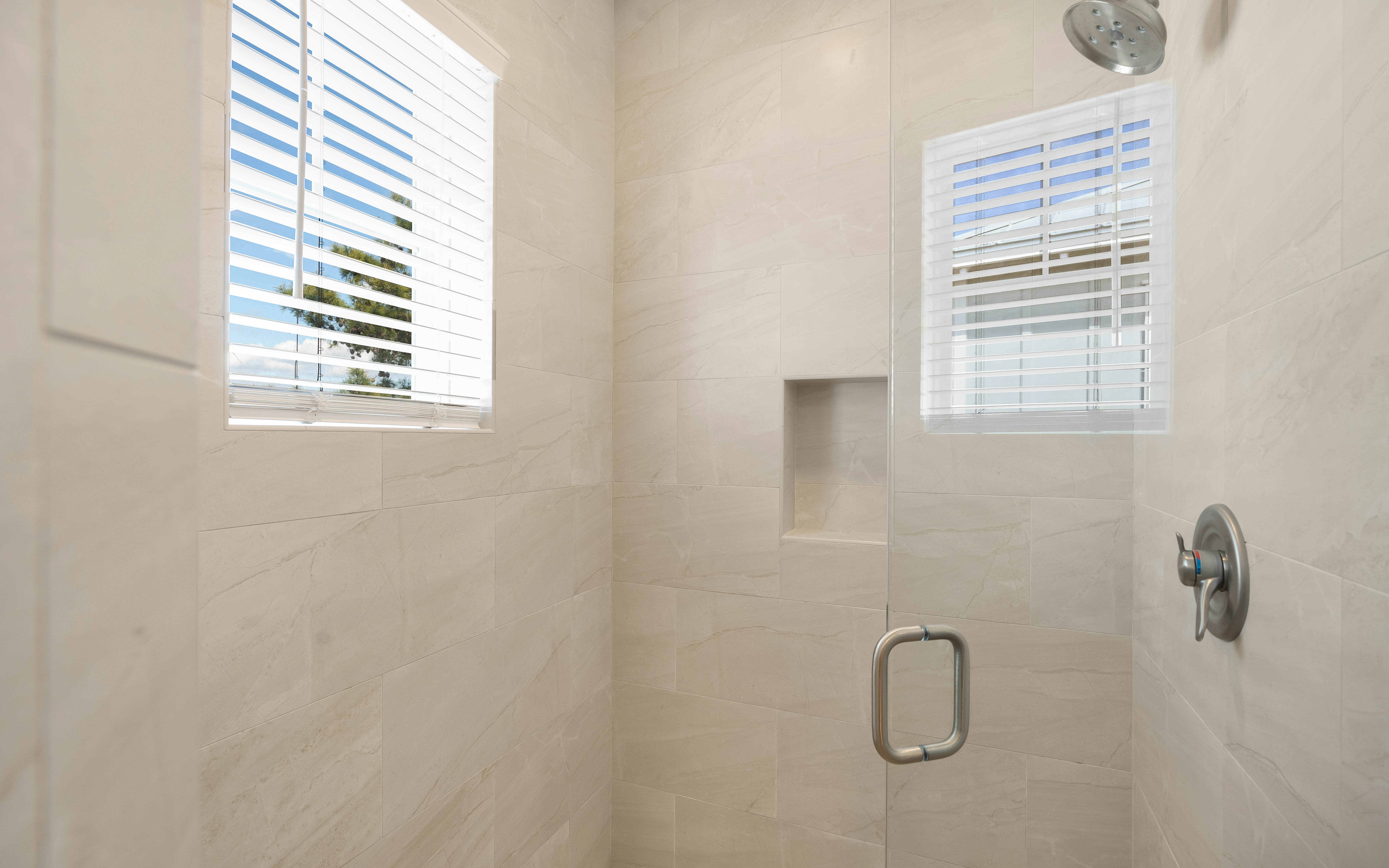 Step into your private shower sanctuary with elegant marble-style tiles and rainfall showerhead for a refreshing morning start.