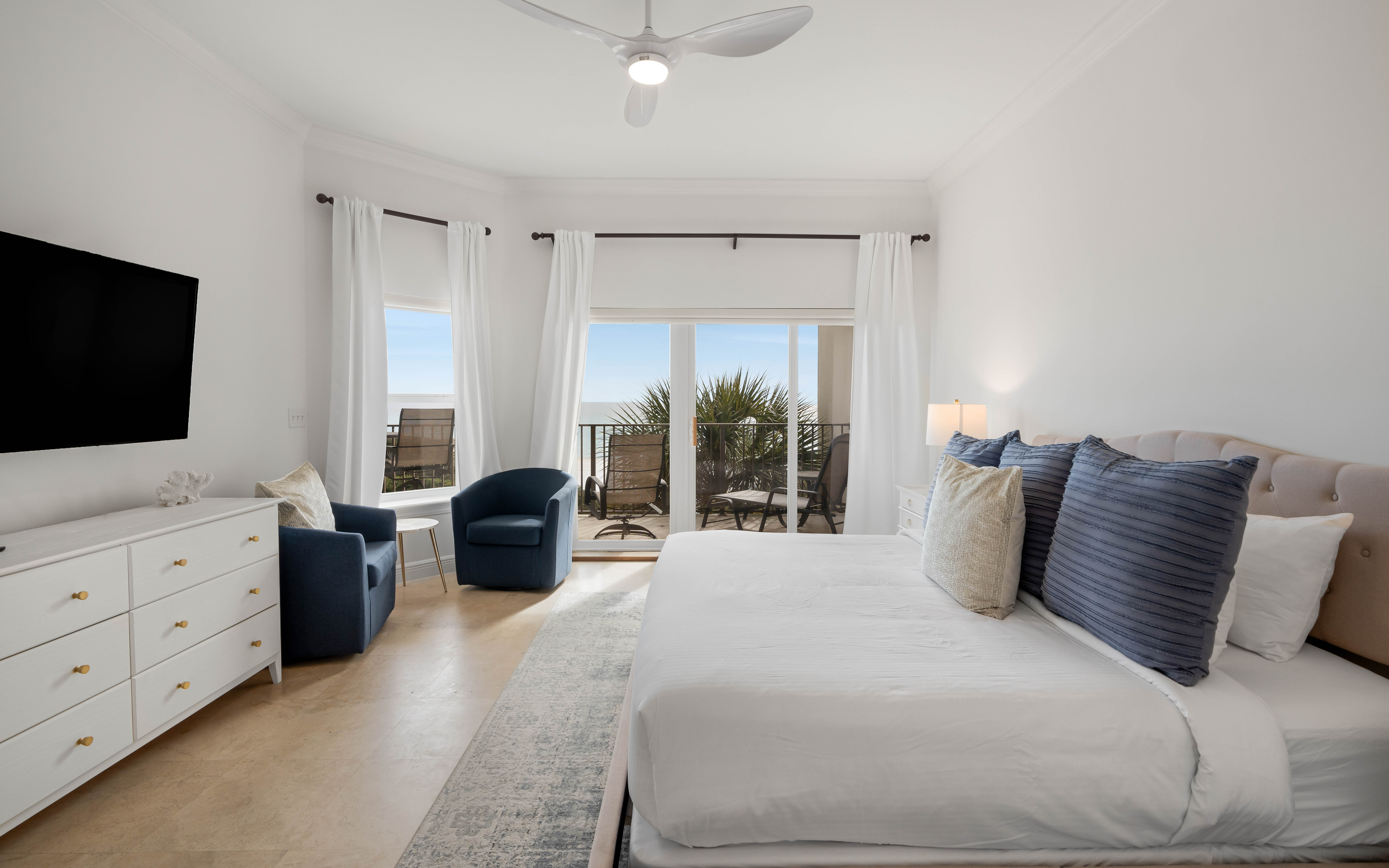 Wake to coastal views from your bright bedroom, complete with balcony access and thoughtful touches like cozy seating.