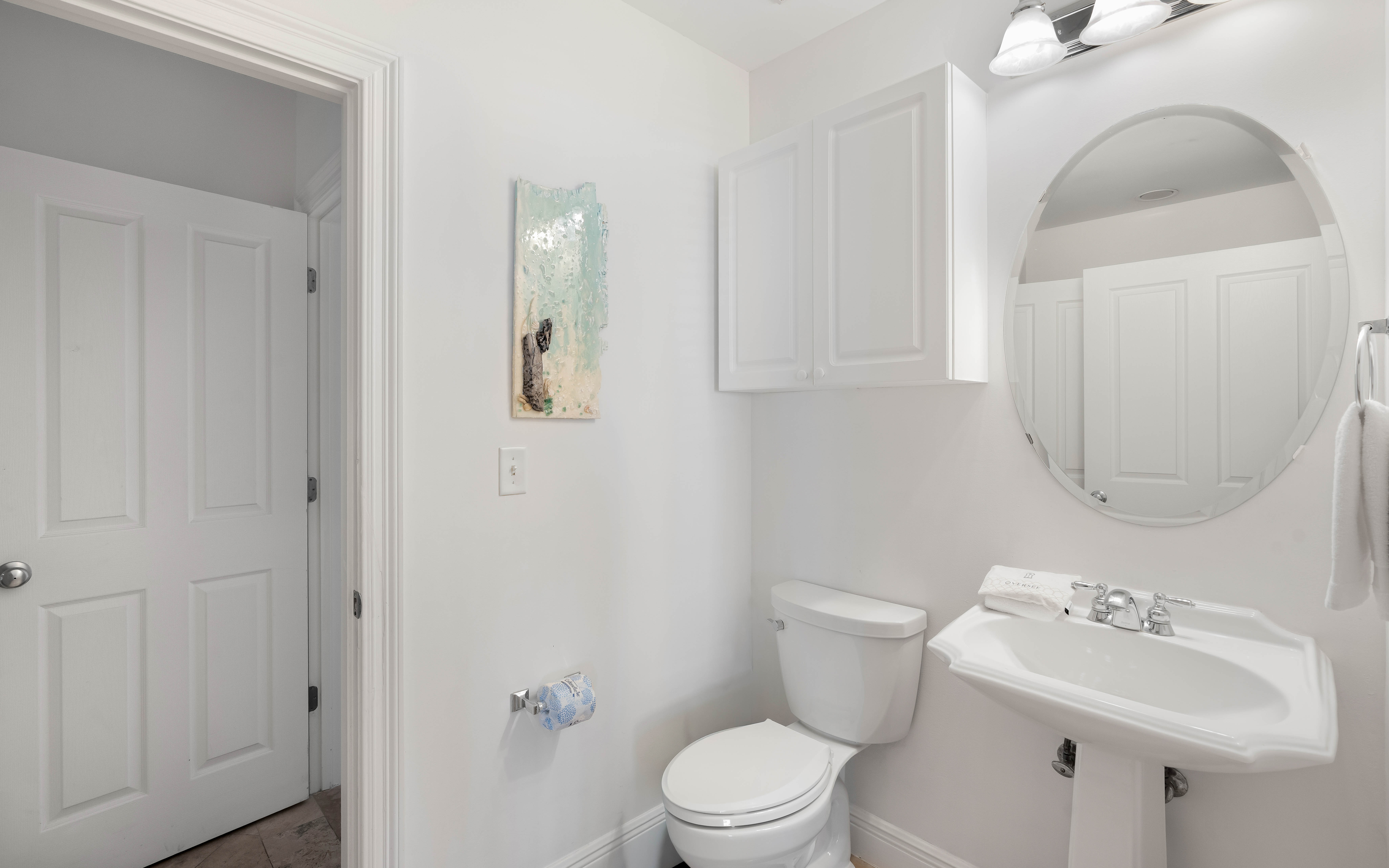 Step into your bright, spotless bathroom featuring a pedestal sink and round mirror—perfect for your morning routine.