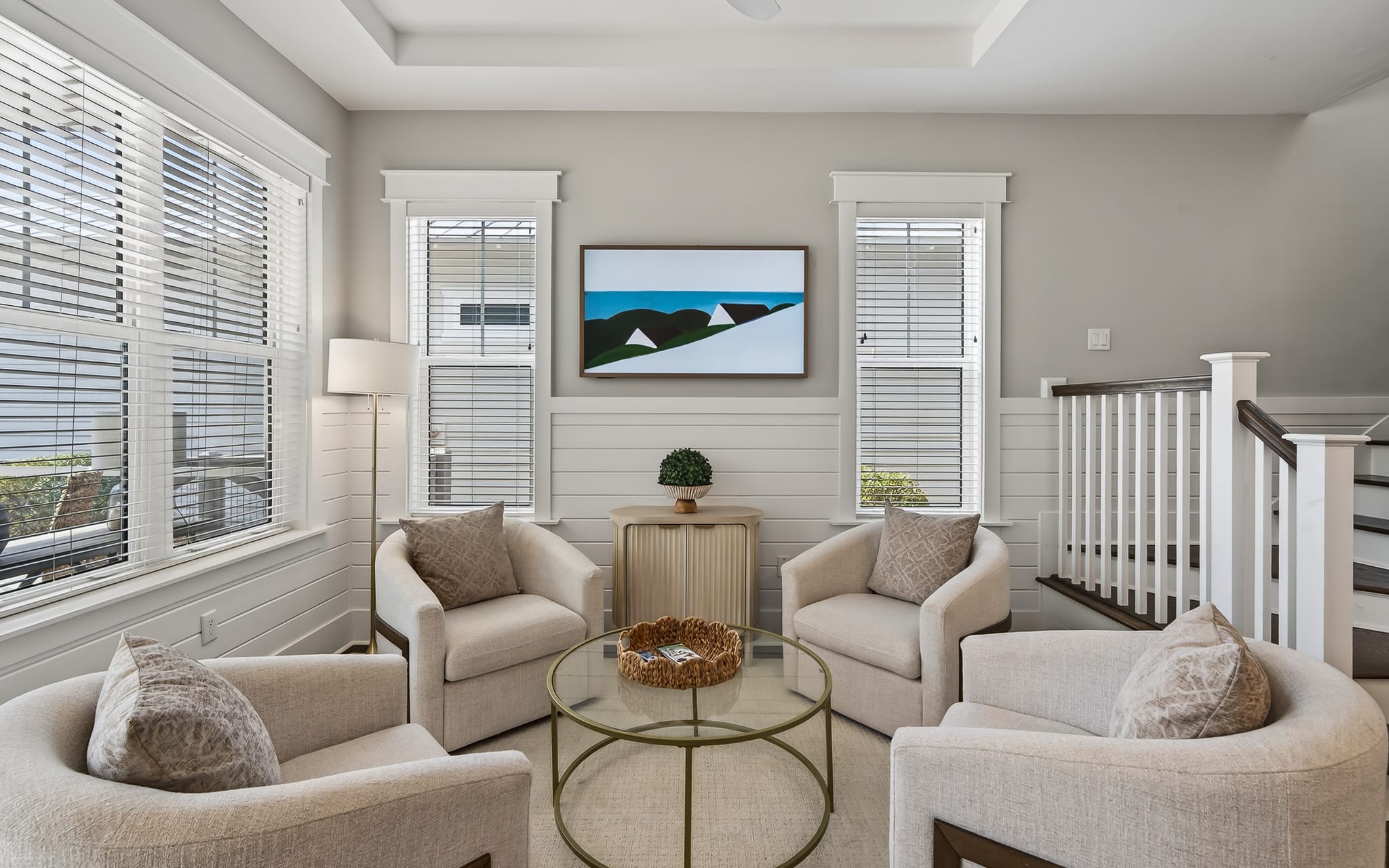 Sink into plush neutral armchairs around your glass coffee table, where natural light streams through elegant blinds.
