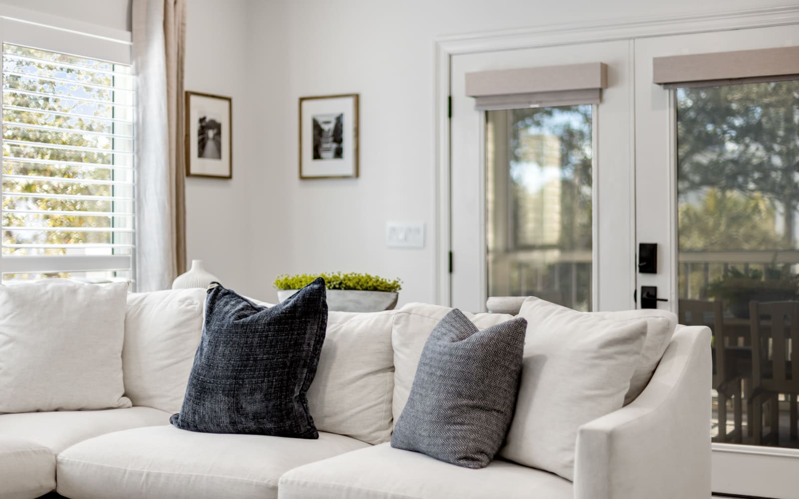 Sink into this plush white sectional where natural light streams through plantation shutters, creating your perfect afternoon reading nook.