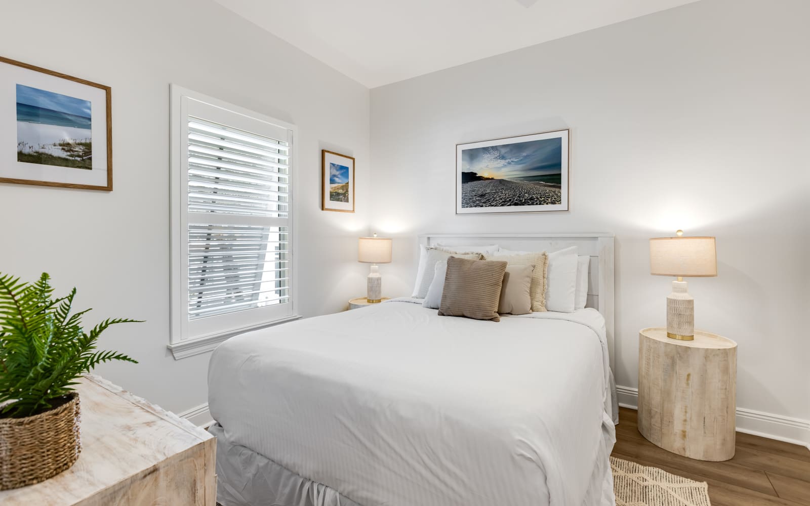 Relax in your serene bedroom featuring coastal artwork, soft lighting, and crisp white linens for the perfect night's sleep.