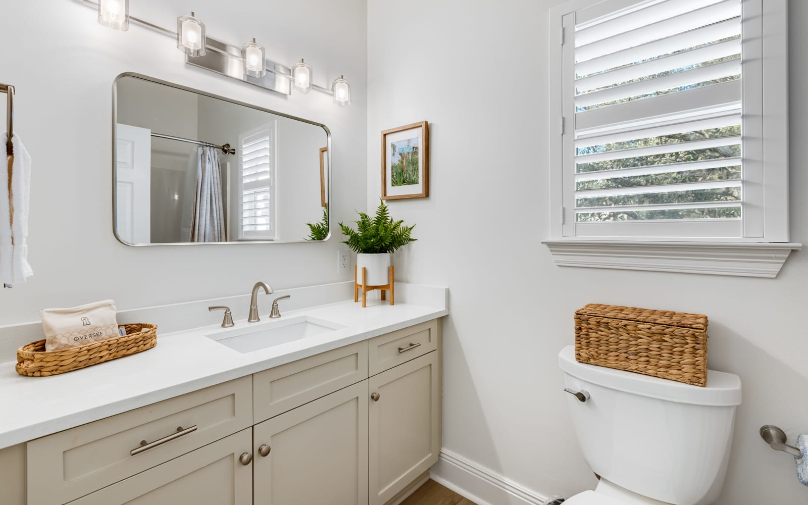 Your pristine bathroom features warm touches like woven baskets and fresh greenery, creating a spa-like retreat for your daily routine.