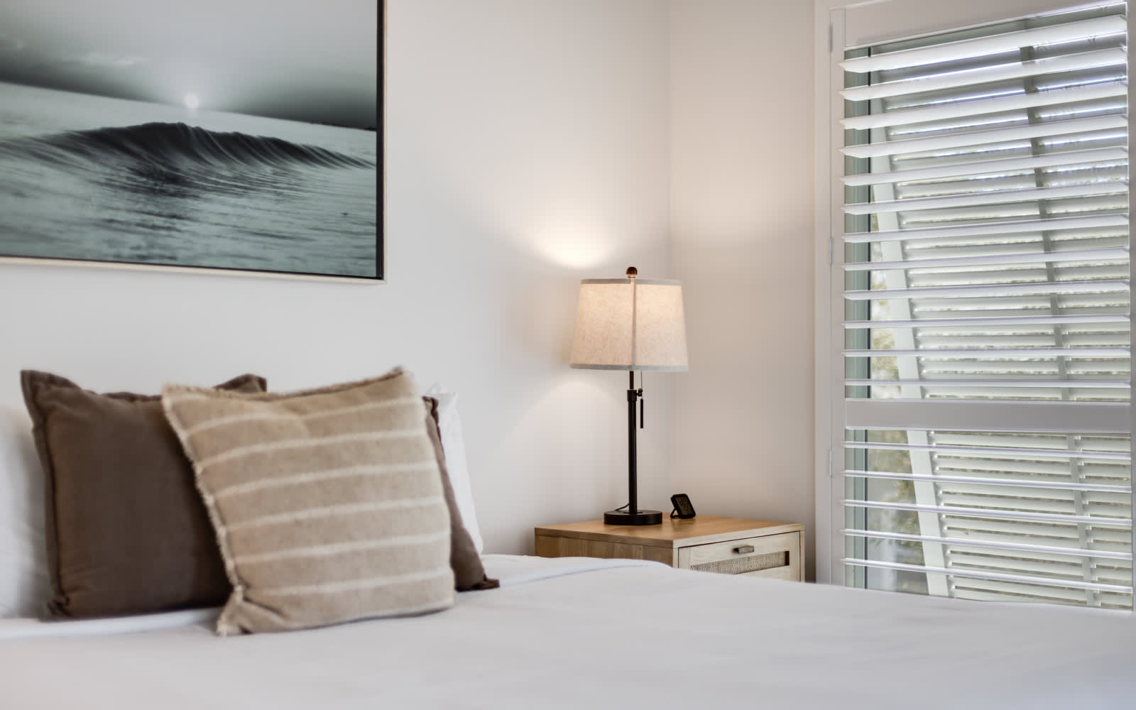 Sink into crisp white linens and plush pillows in your peaceful bedroom retreat, where ocean-inspired art creates tranquil vibes.