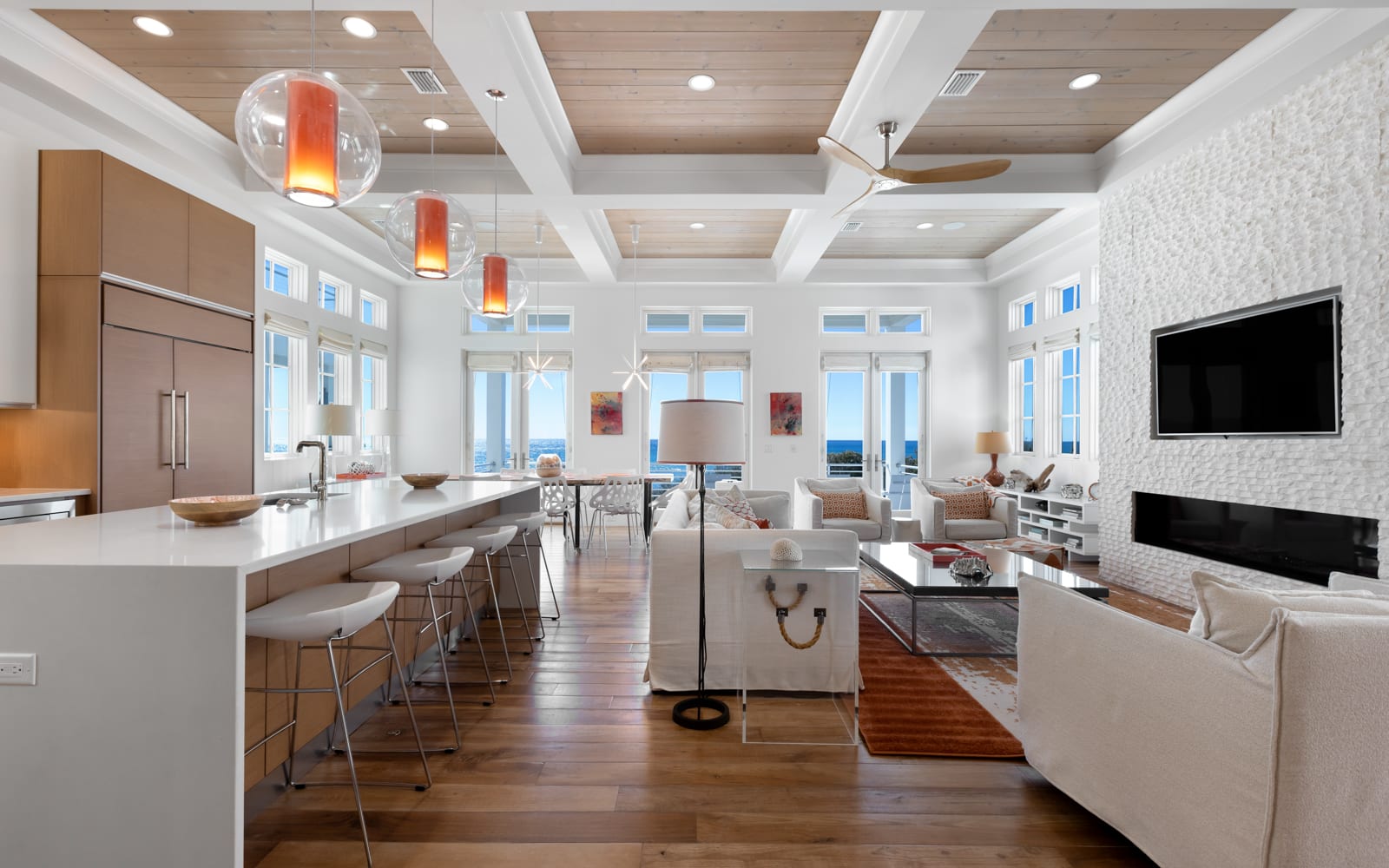 Relax in this stunning open-concept space where modern kitchen flows into elegant living area with fireplace and ocean views.