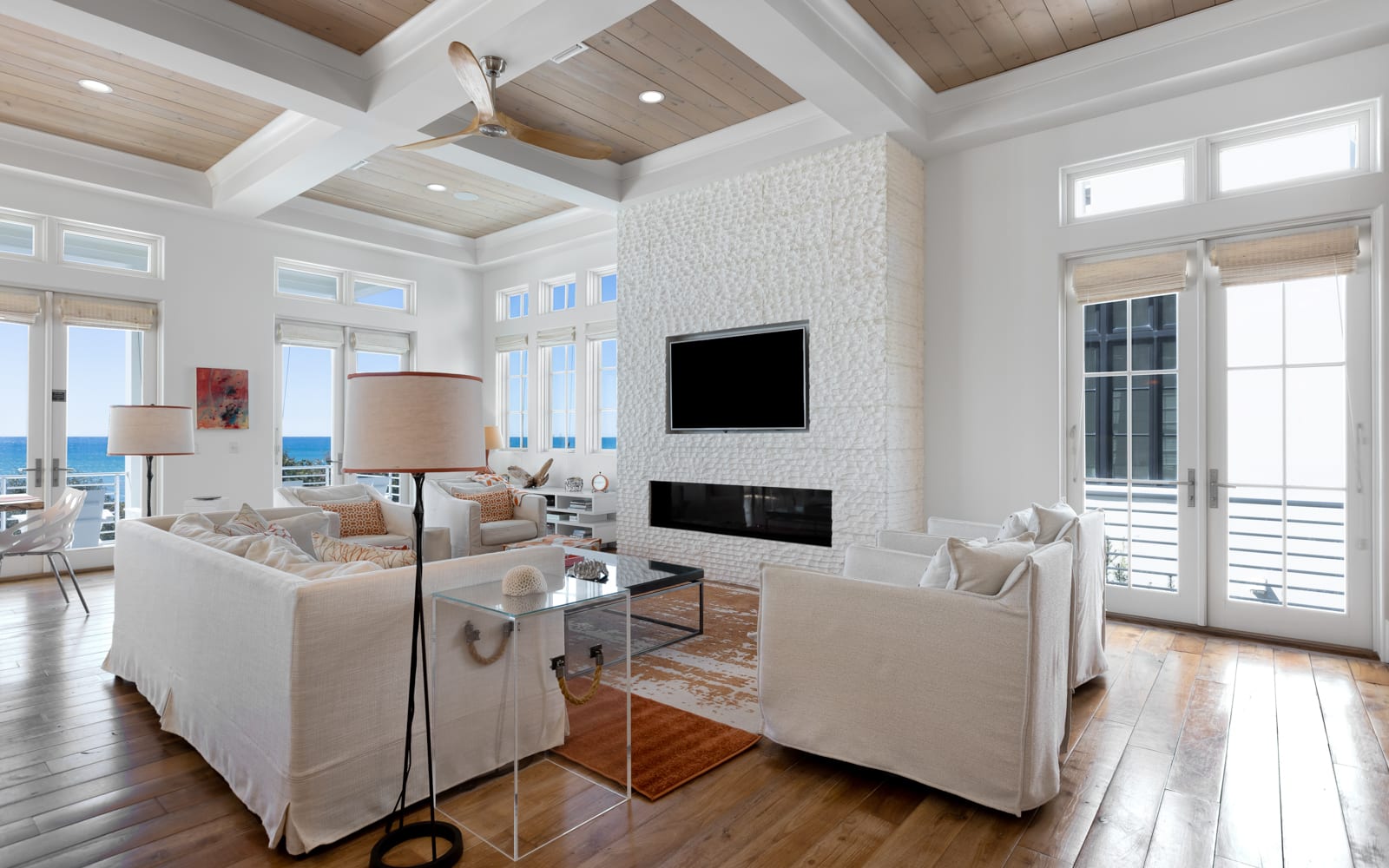 Unwind in your elegant living space with soaring coffered ceilings, cozy fireplace, and stunning ocean views through floor-to-ceiling windows.