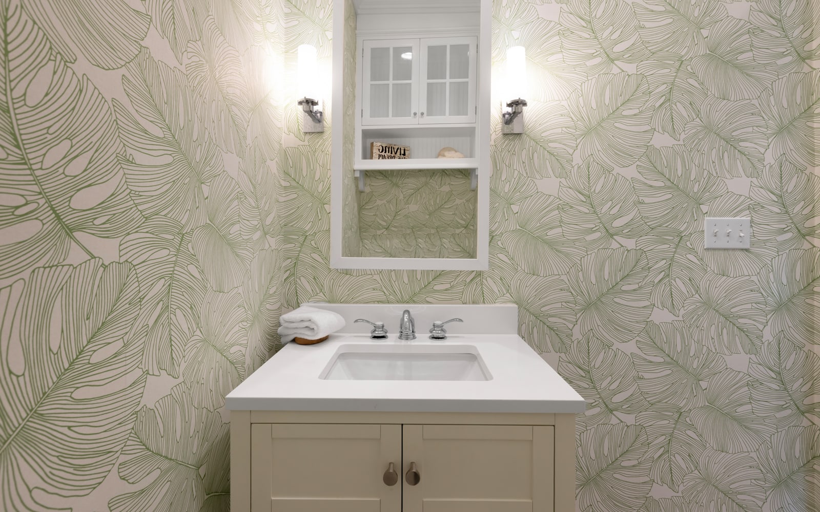 Fresh tropical wallpaper transforms your powder room into a stylish retreat with crisp white vanity and thoughtful details.