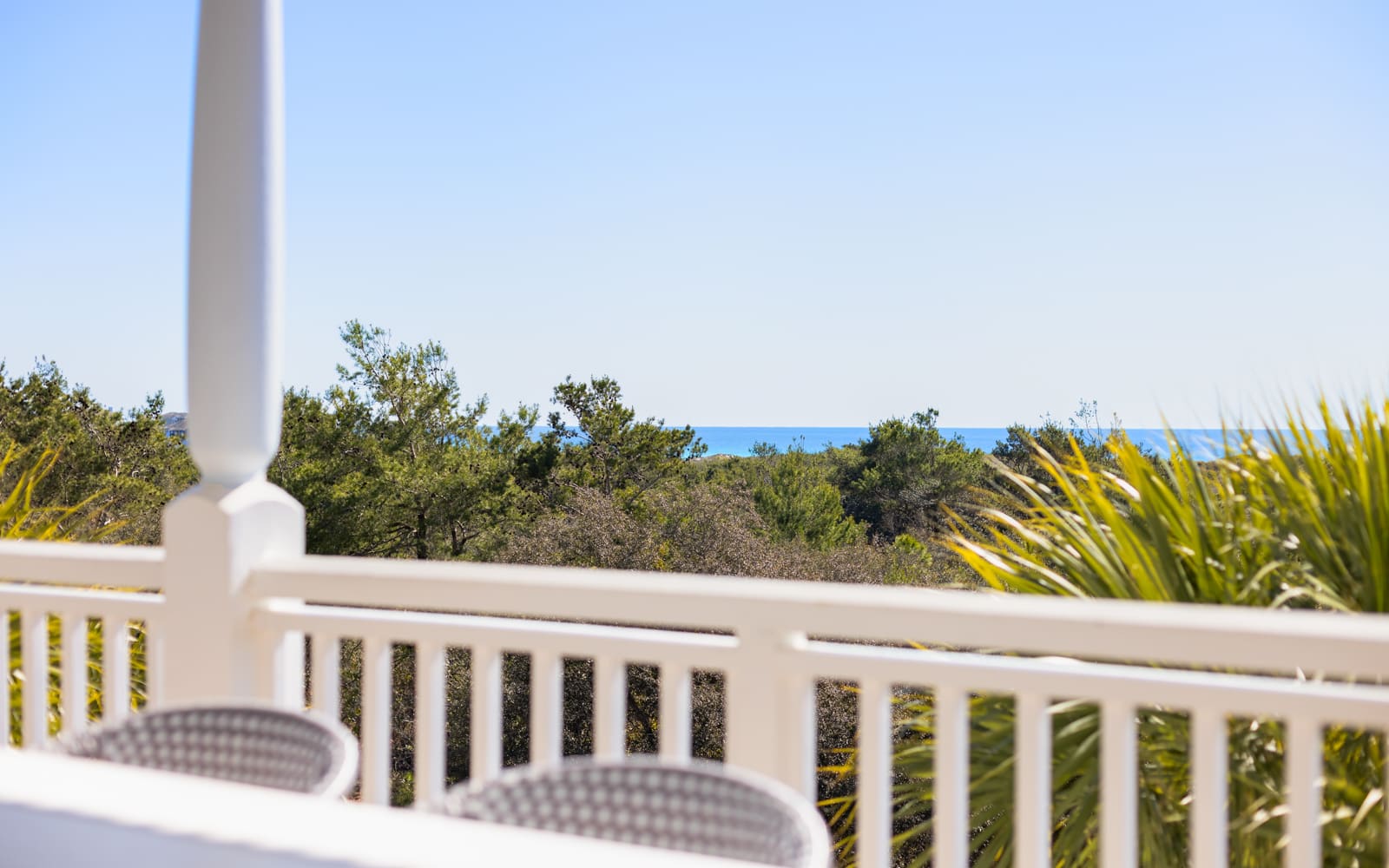 Peaceful balcony overlooks lush greenery and distant ocean views, creating the perfect spot for morning coffee or evening relaxation.