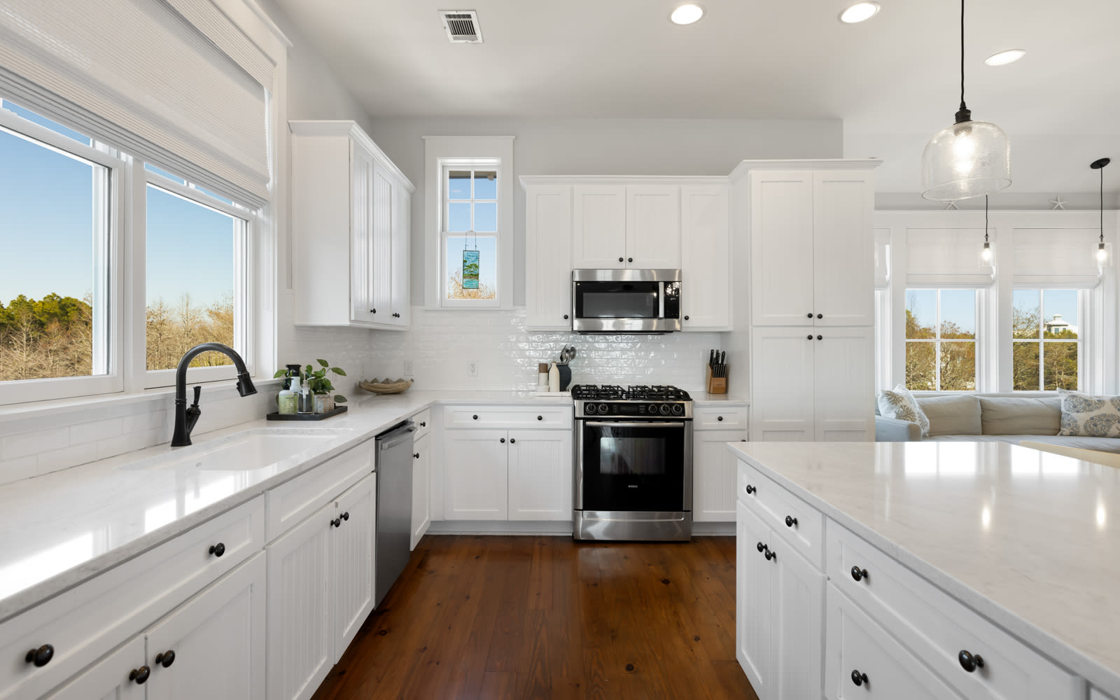 You'll love preparing meals in this bright, modern kitchen with gleaming white cabinets, spacious countertops, and premium appliances bathed in natural light.