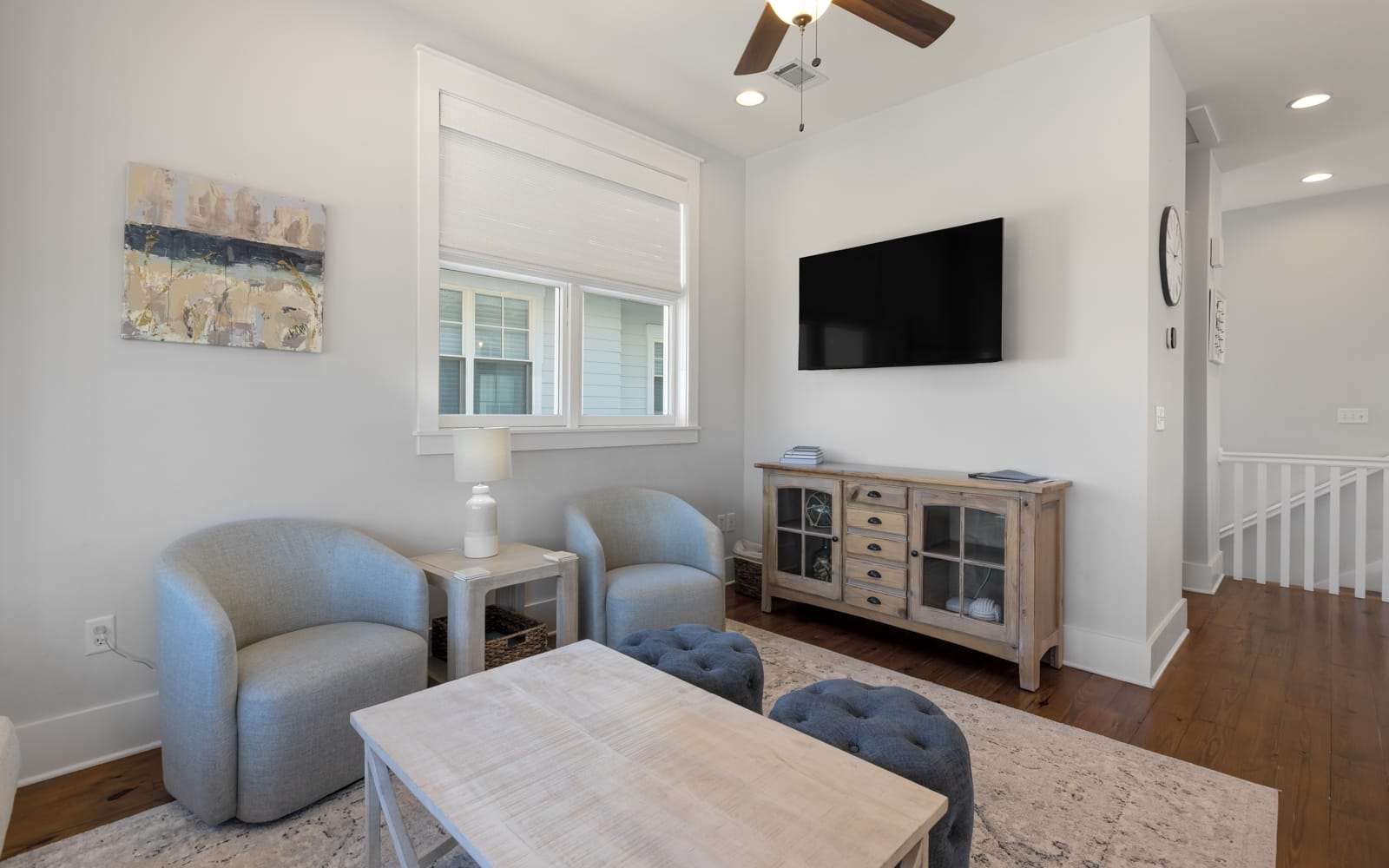 Unwind in your cozy living room with plush seating, entertainment center, and calming coastal artwork creating the perfect retreat.