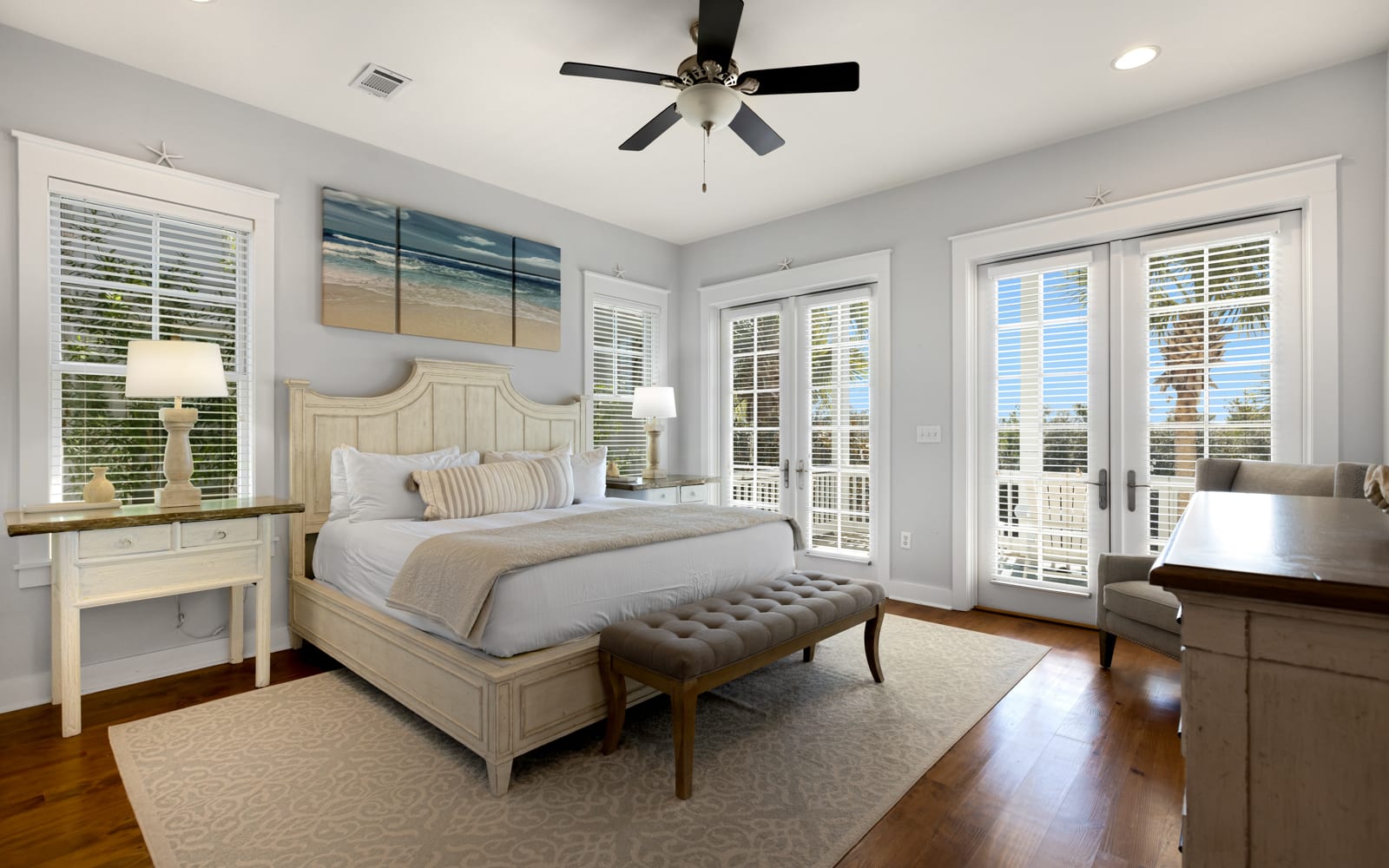 Your serene master bedroom features coastal charm with ocean artwork, French doors to your private balcony, and elegant furnishings for restful nights.