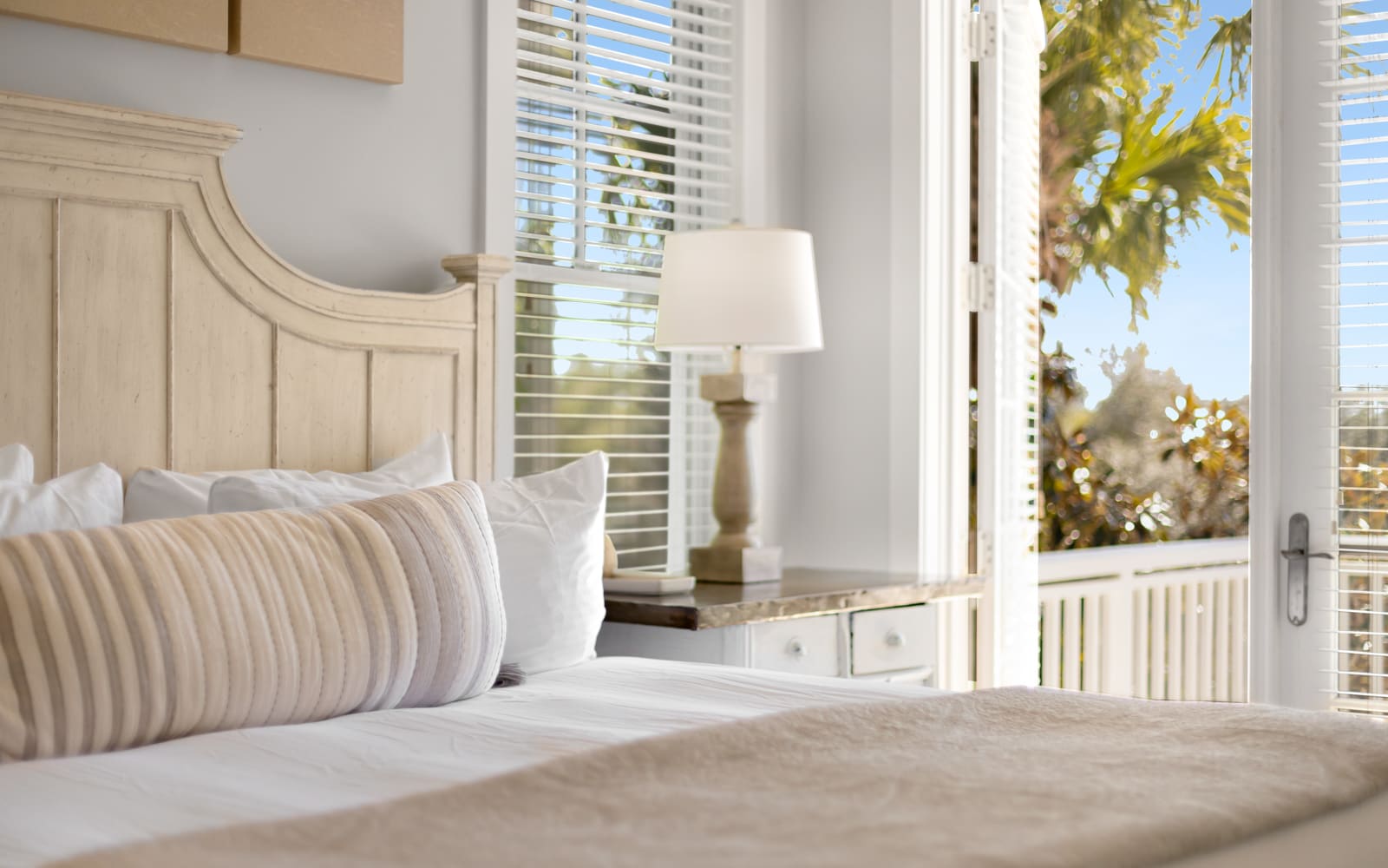 Wake up to tropical views streaming through your private balcony doors, where soft linens and coastal charm create your perfect retreat.