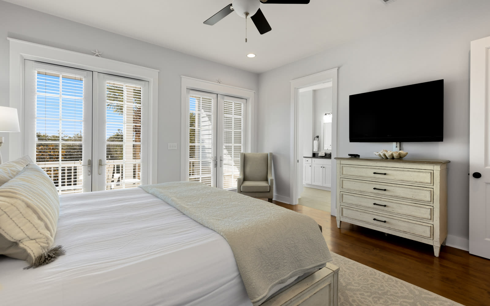 Wake up refreshed in your serene bedroom with plush bedding, modern TV, and French doors opening to peaceful views.