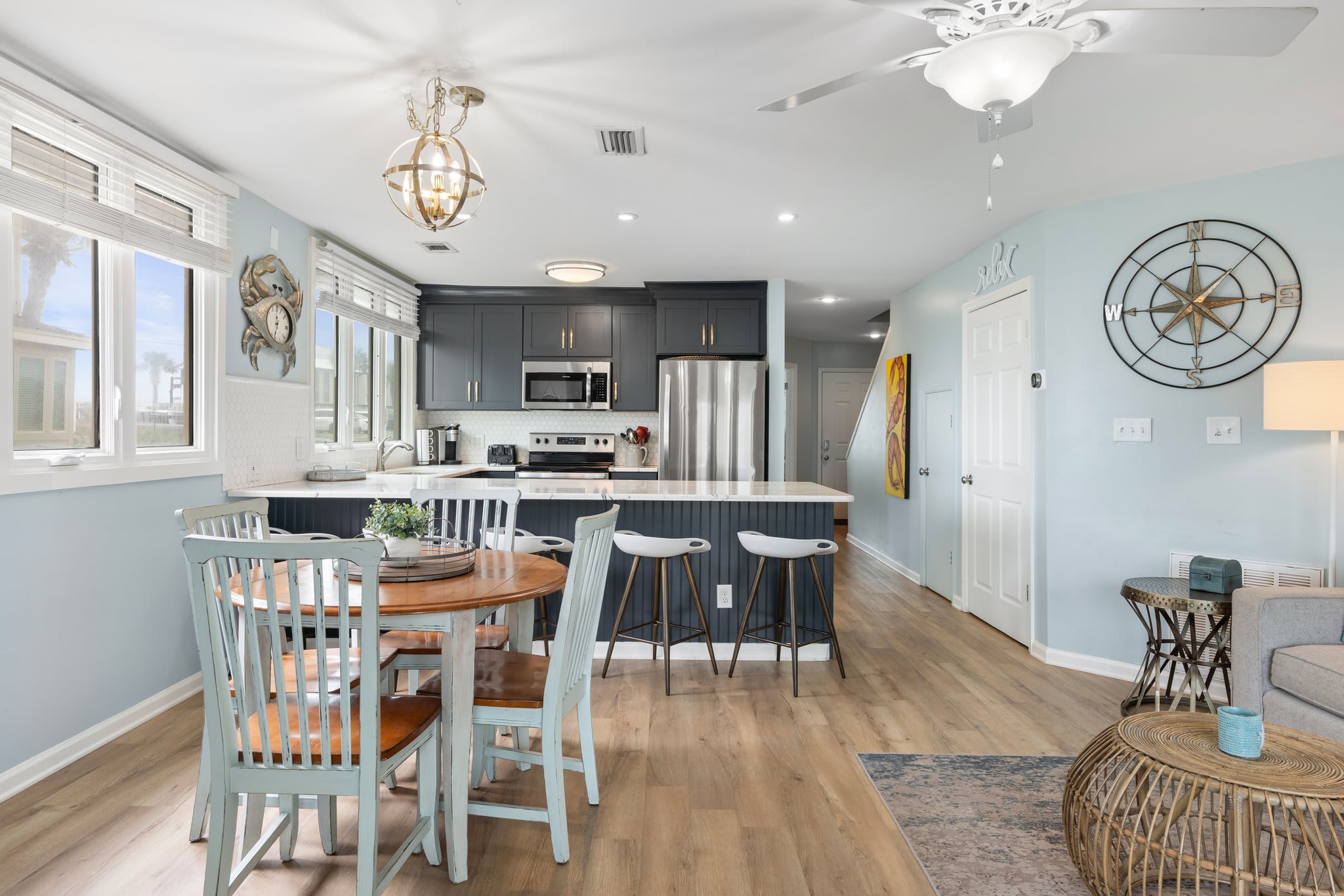 Open-concept dining and kitchen area with a coastal vibe features a round table for four, bar seating for five, and modern finishes—ideal for meals and memories with family and friends.