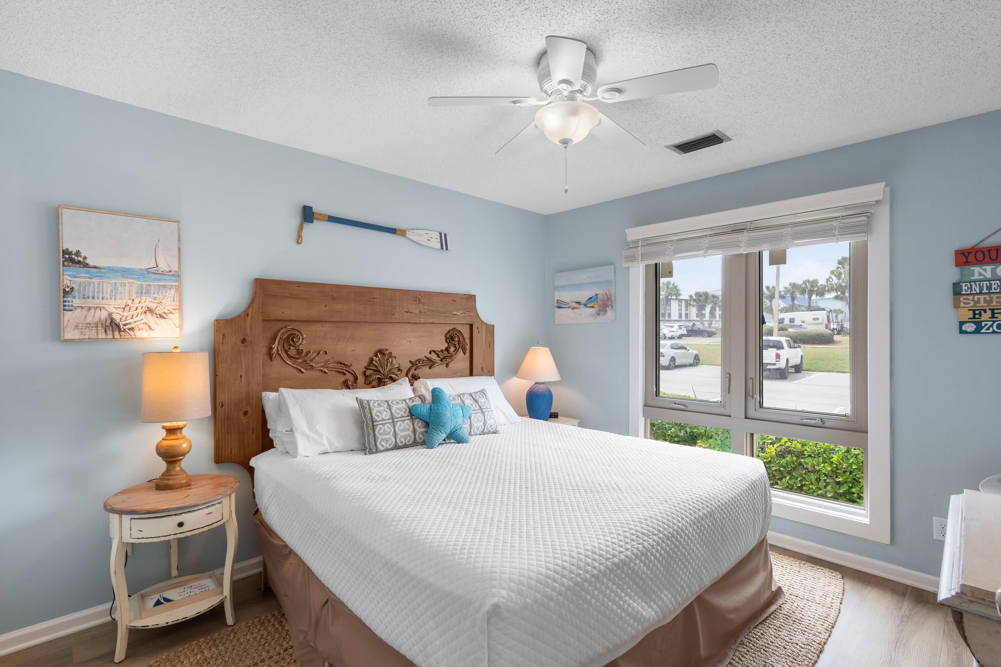 Guest bedroom with soft coastal colors, plush bedding, and charming nautical décor. Large windows brighten the space, creating a cozy and inviting retreat for friends or family.