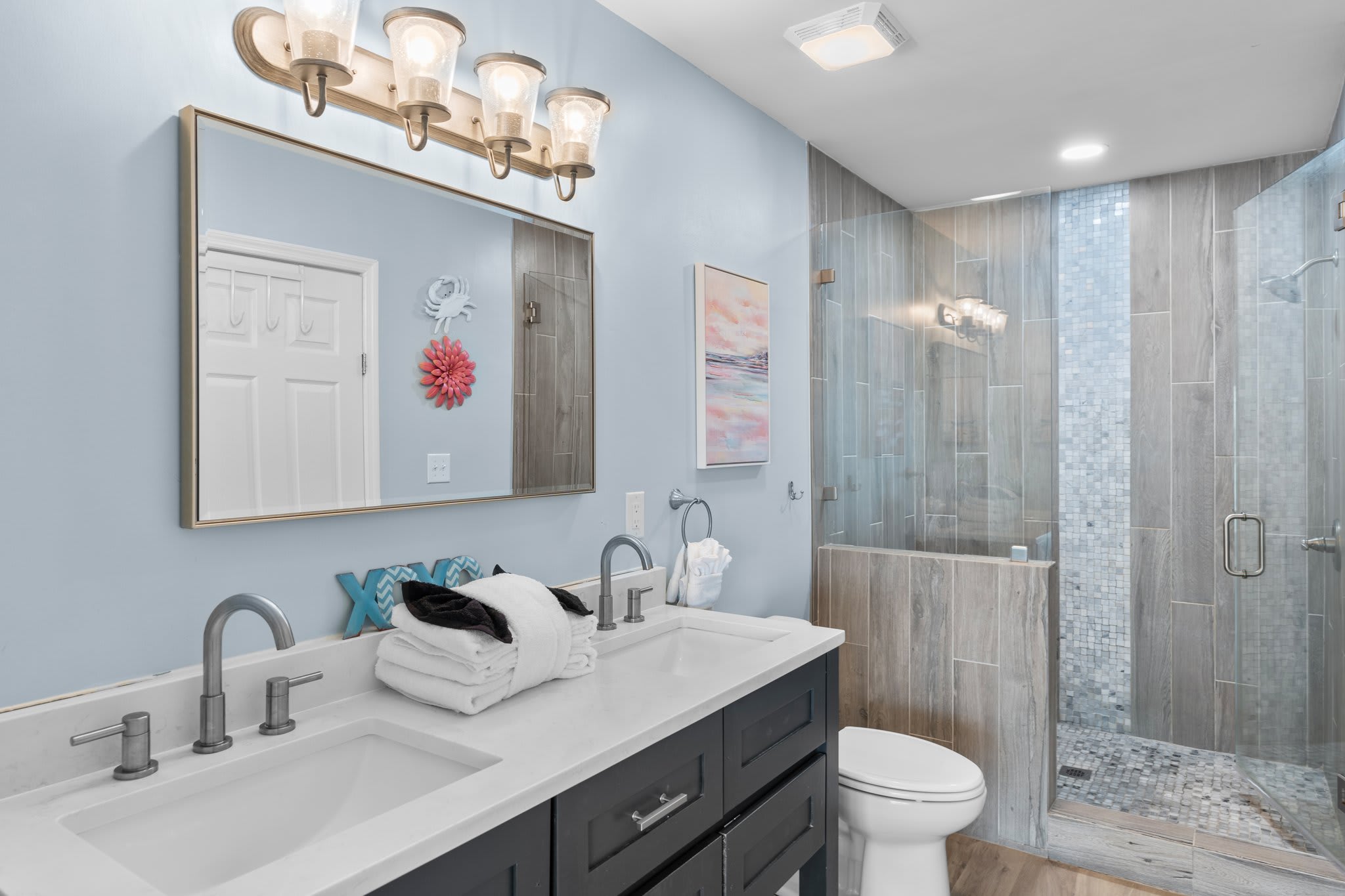 Elegant en-suite bathroom with double vanity, quartz countertop, and a spa-style walk-in shower—designed with coastal charm and modern finishes for a refreshing retreat.