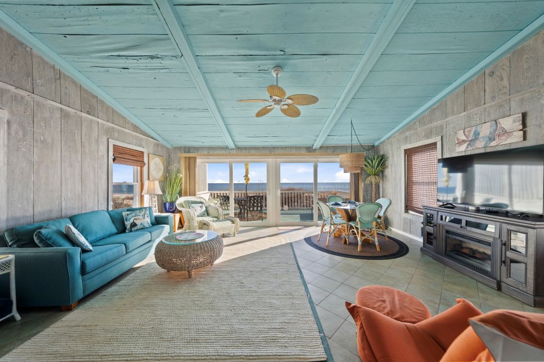 Relax in your bright coastal living room with ocean views, turquoise sofa, and modern kitchen—your perfect beachfront retreat awaits.
