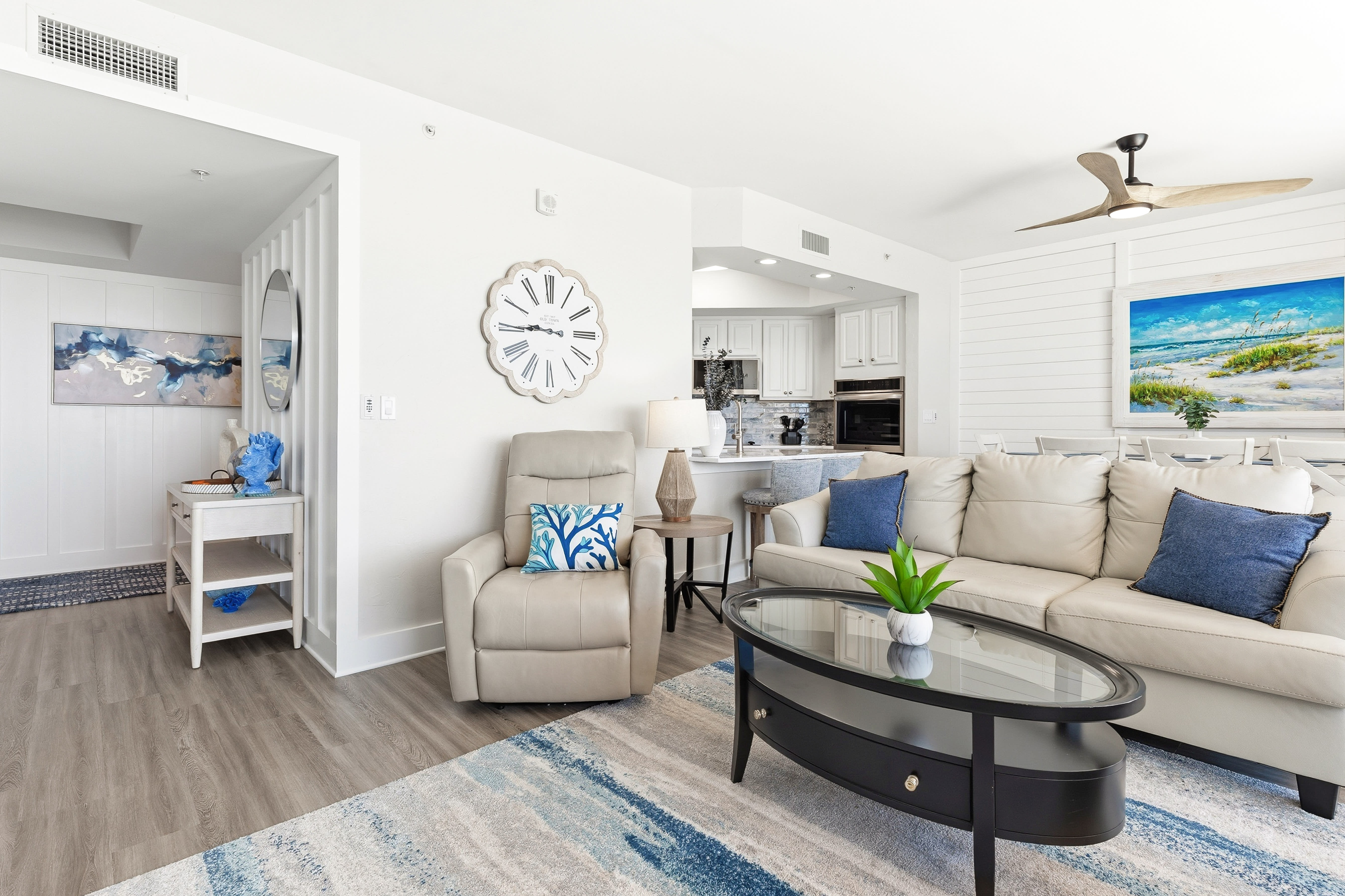 Relax in this coastal-inspired living space with plush seating, ocean artwork, and modern amenities including air conditioning for your comfort.