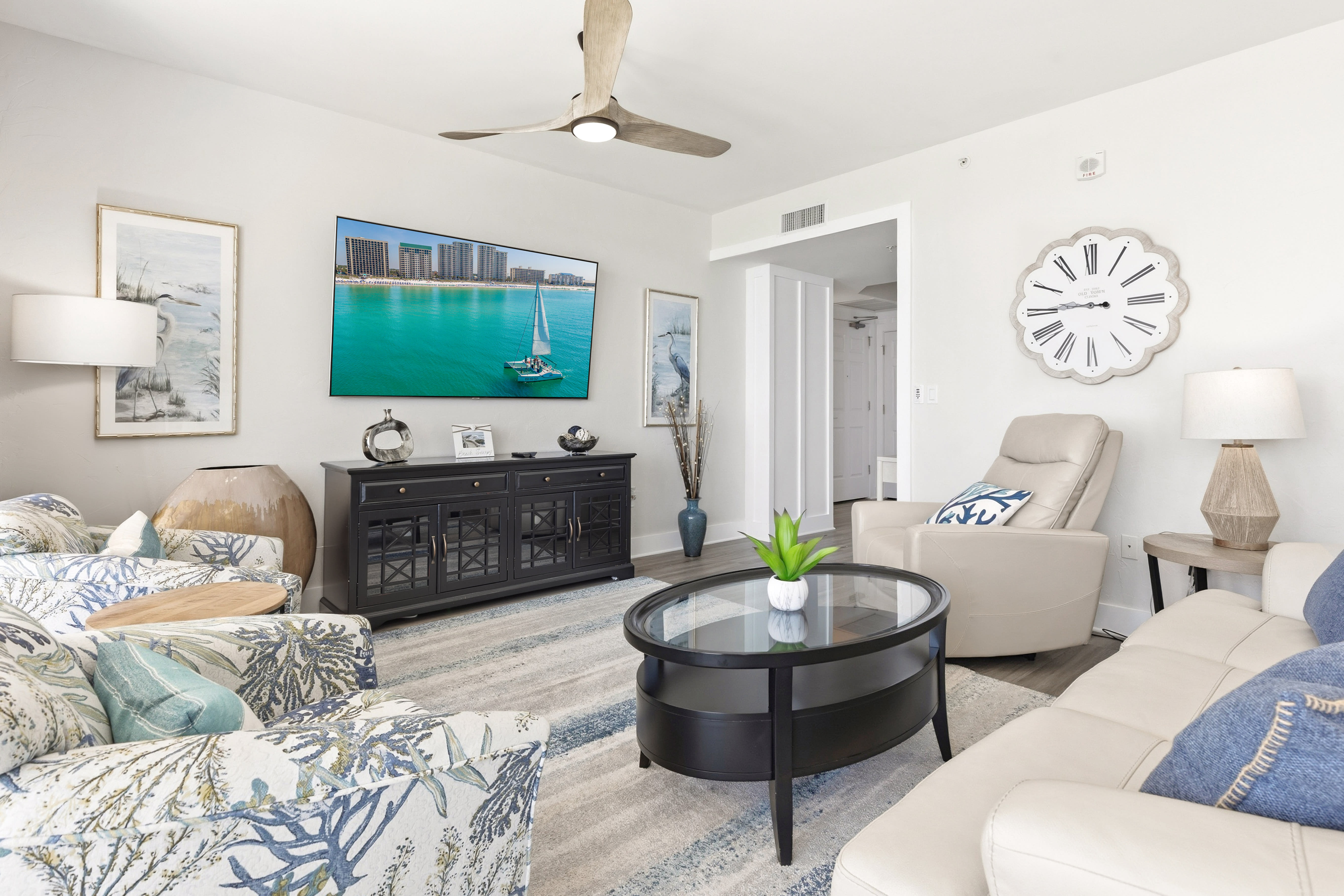 Relax in your coastal-themed living room with comfortable seating and entertainment center, perfect for unwinding after beach days.