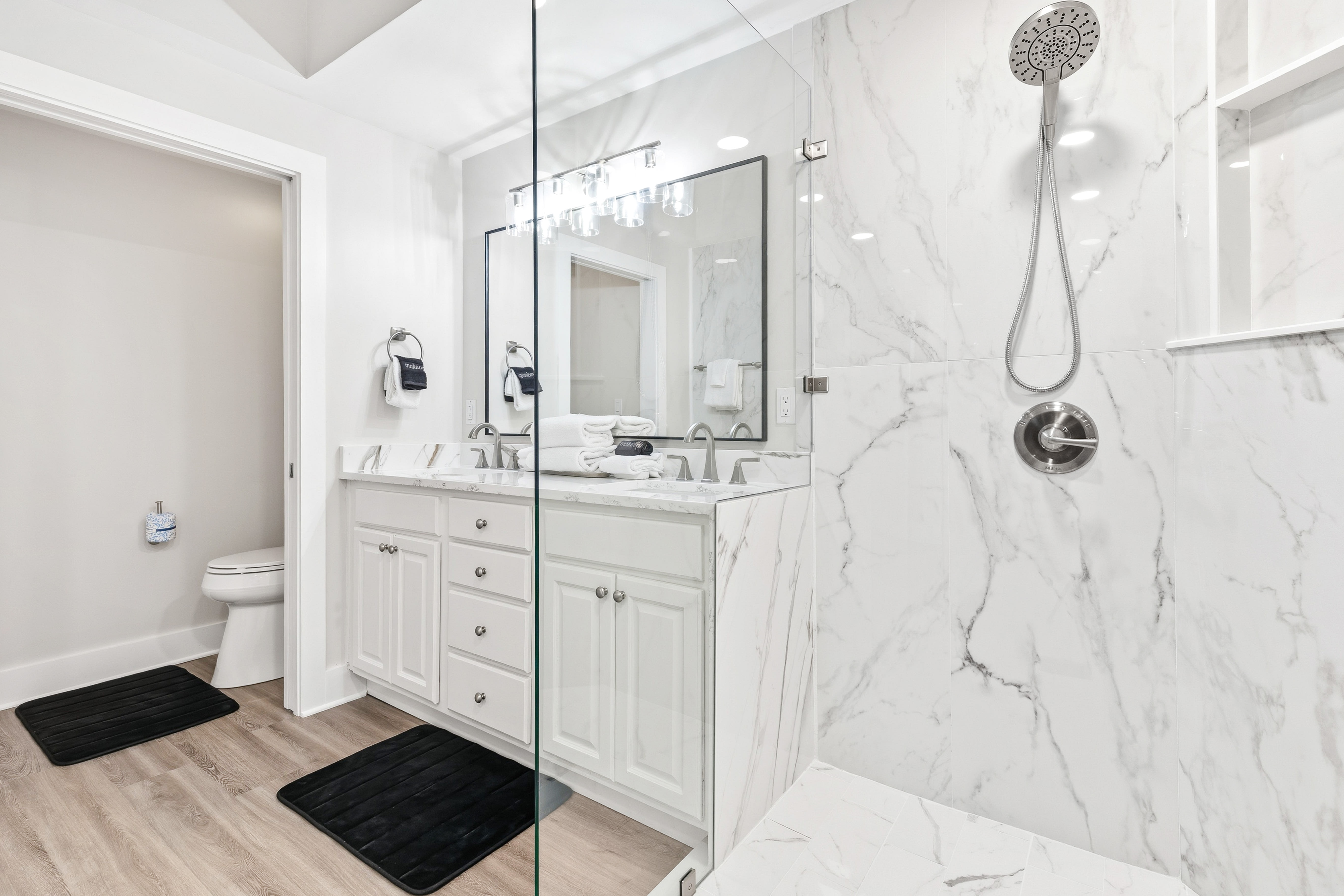 Step into your luxurious marble-adorned bathroom with sleek glass shower and dual vanities for ultimate comfort.