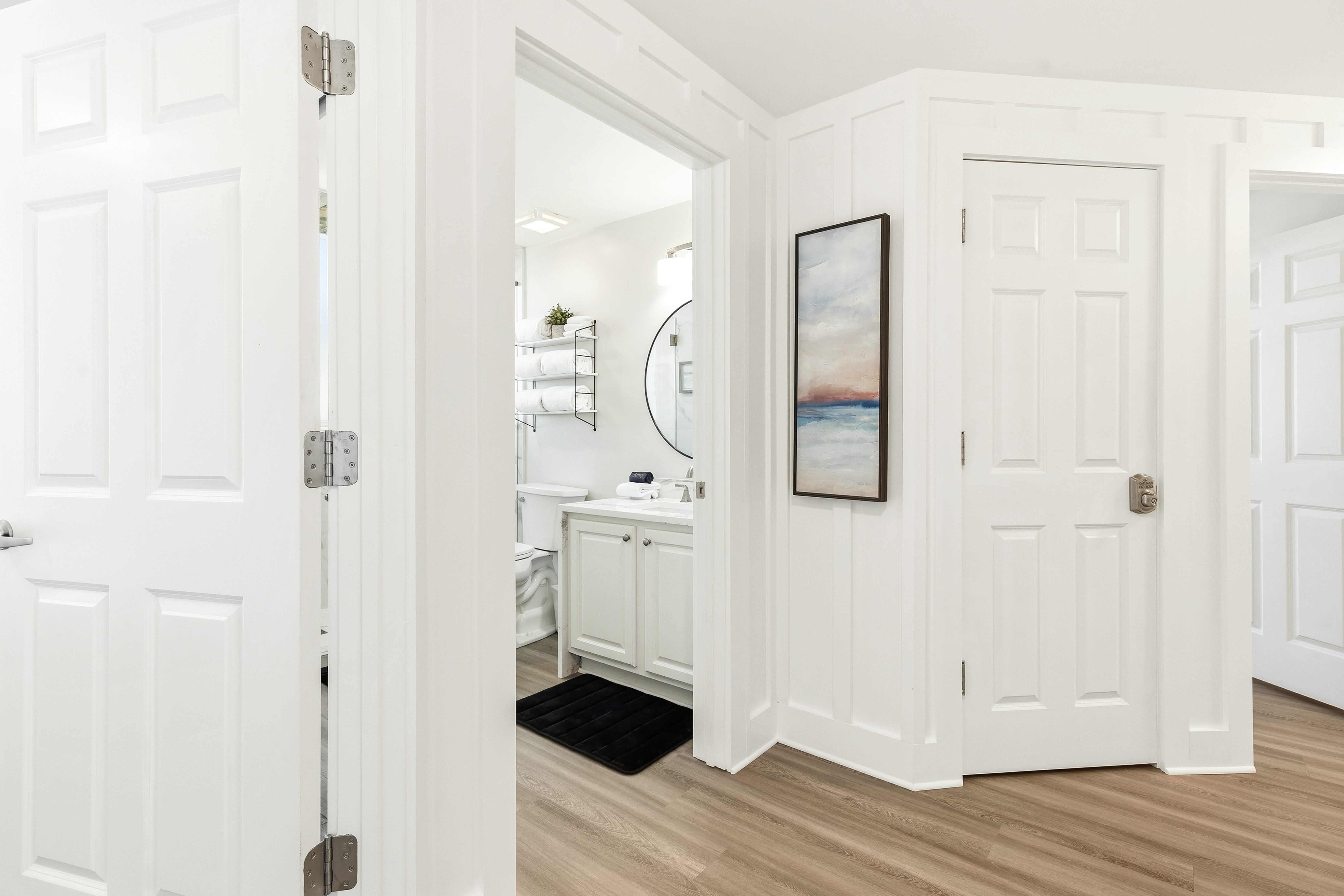 Step into your bright, welcoming hallway where crisp white doors lead to your private bathroom retreat.