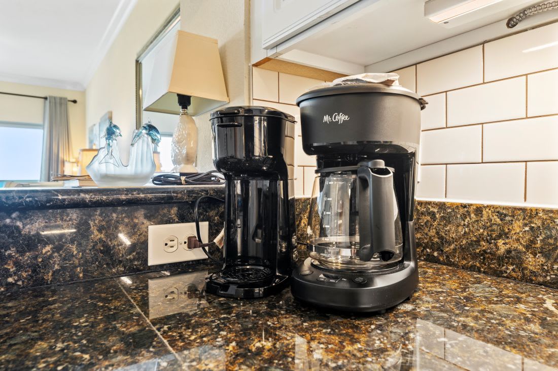 Start your morning right with fresh coffee from your fully equipped kitchen counter featuring premium appliances and granite surfaces.