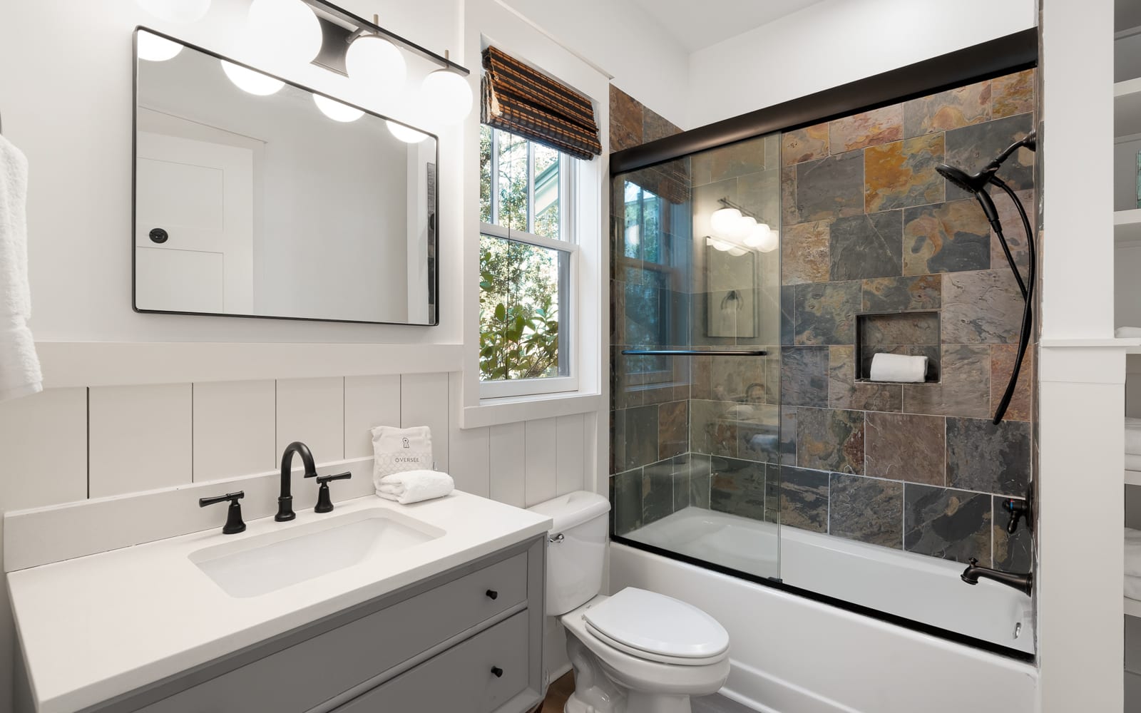 Unwind in your elegant bathroom featuring a luxurious slate-tiled shower and pristine vanity, perfectly designed for your comfort.