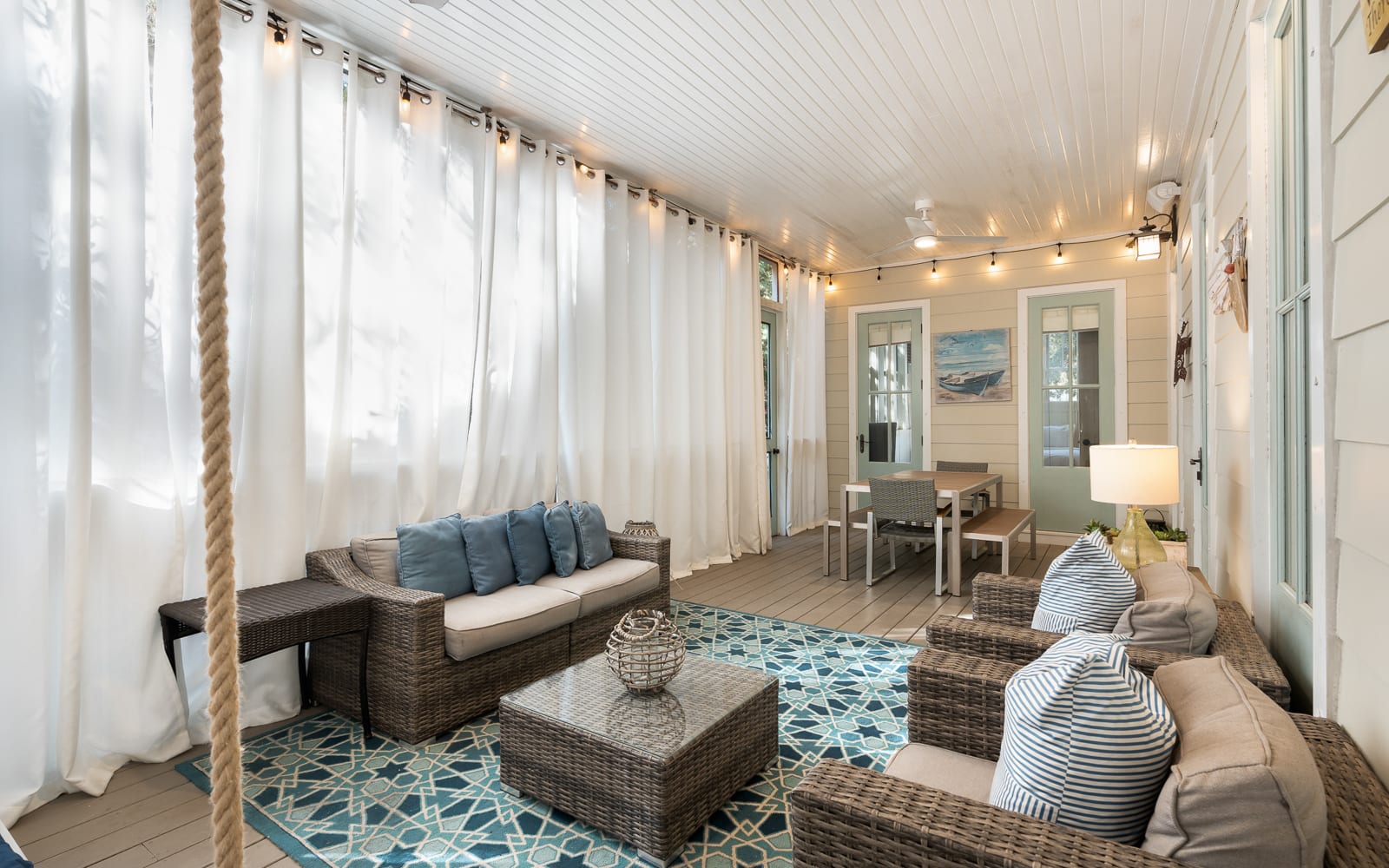 Your private porch retreat features cozy wicker seating, soft nautical pillows, and twinkling string lights creating the perfect spot to unwind.
