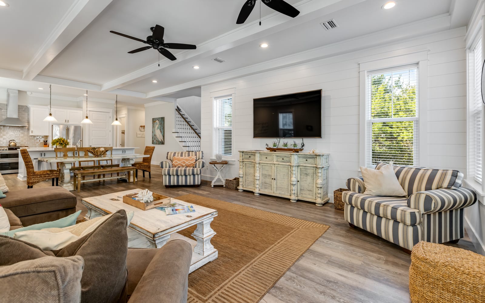 Relax in your spacious coastal living room with soaring ceilings, cozy seating, and natural light streaming through large windows.