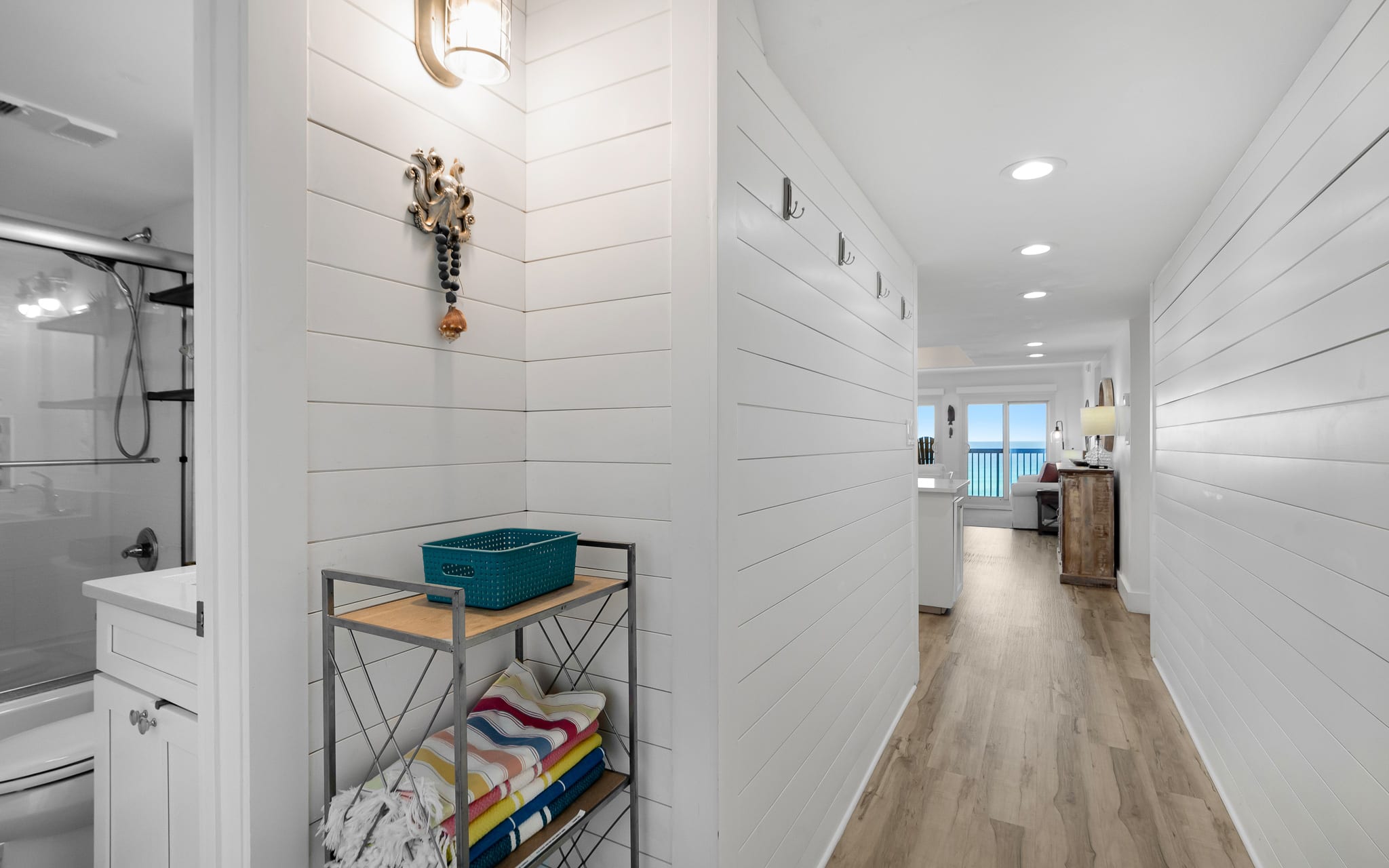 Walk through your bright hallway past the organized bathroom and into your coastal living space with gulf views beyond.
