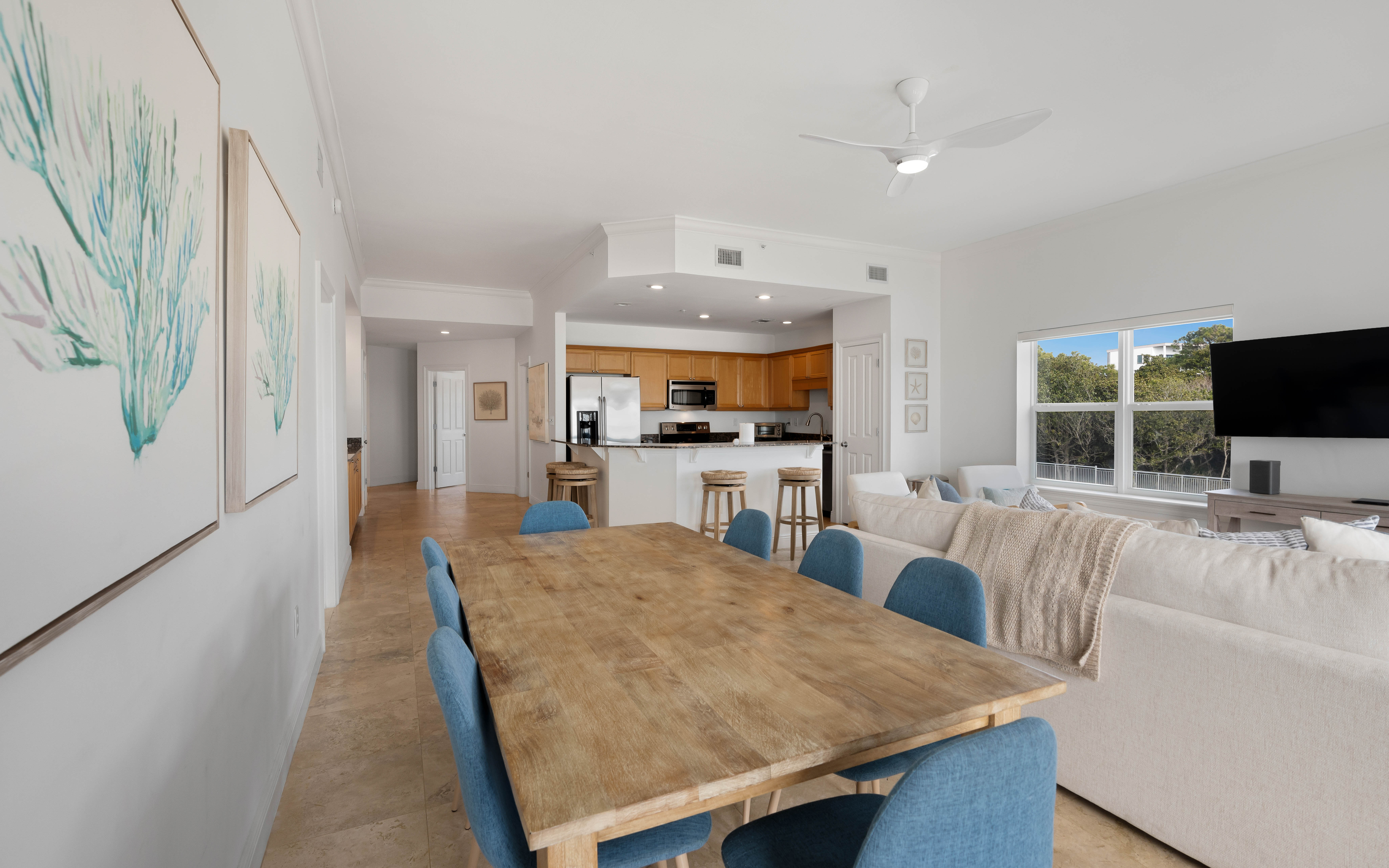 Relax in your spacious open-plan living area where coastal artwork and blue accents create a serene atmosphere for dining and unwinding together.