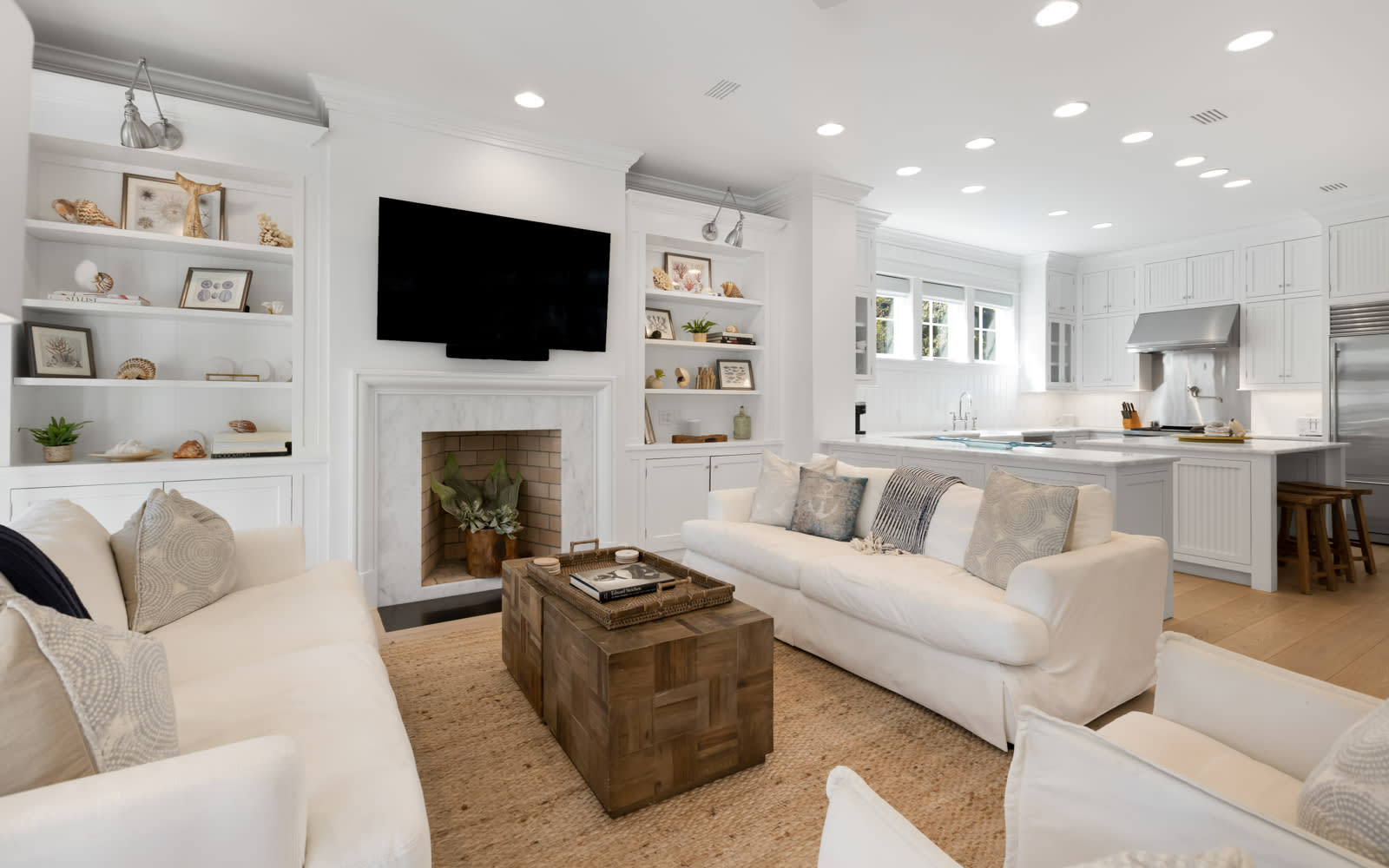 Sink into plush white sofas by the fireplace while your favorite shows play on the wall-mounted TV in this bright, open living space.
