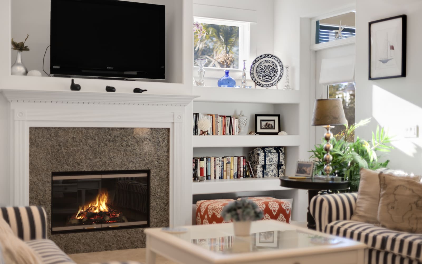 Relax in your bright living room where a crackling fireplace warms the space beneath your mounted TV and curated bookshelf.