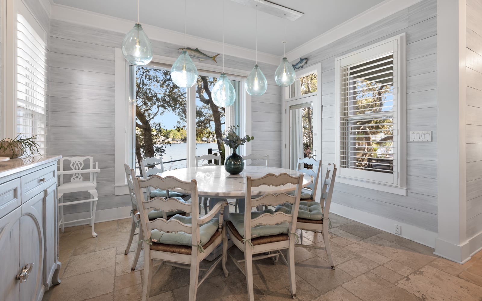Gather around this charming dining table where coastal pendant lights cast a warm glow over your meals with stunning lake views.