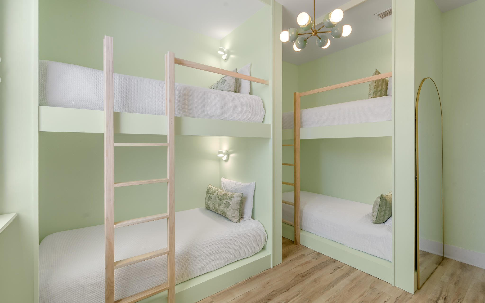 Rest easy in your stylish bunk bed sanctuary with soft green walls and modern lighting creating a peaceful retreat.