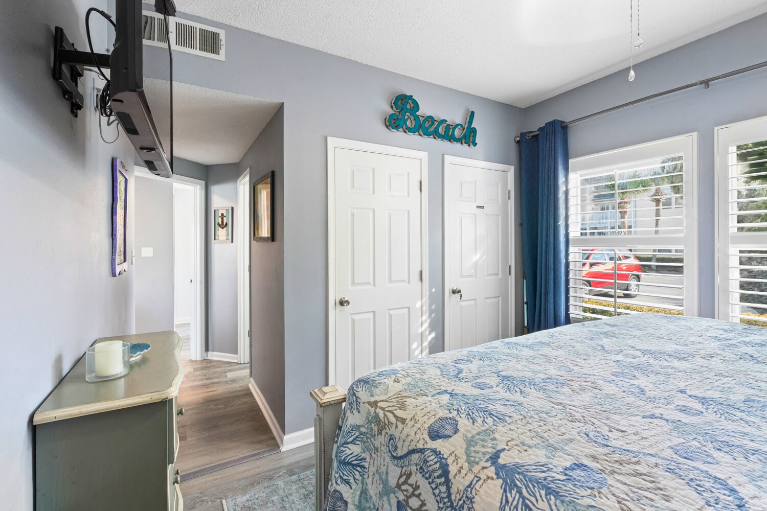 Drift off to peaceful sleep in your beach-themed bedroom with coastal colors and natural light streaming through shuttered windows.