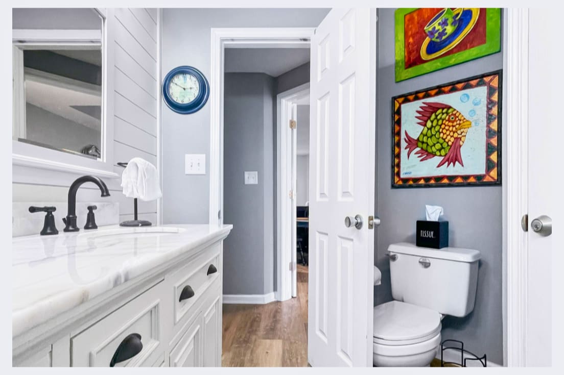 Your stylish bathroom features marble countertops, elegant fixtures, and vibrant coastal artwork creating a fresh, welcoming space.