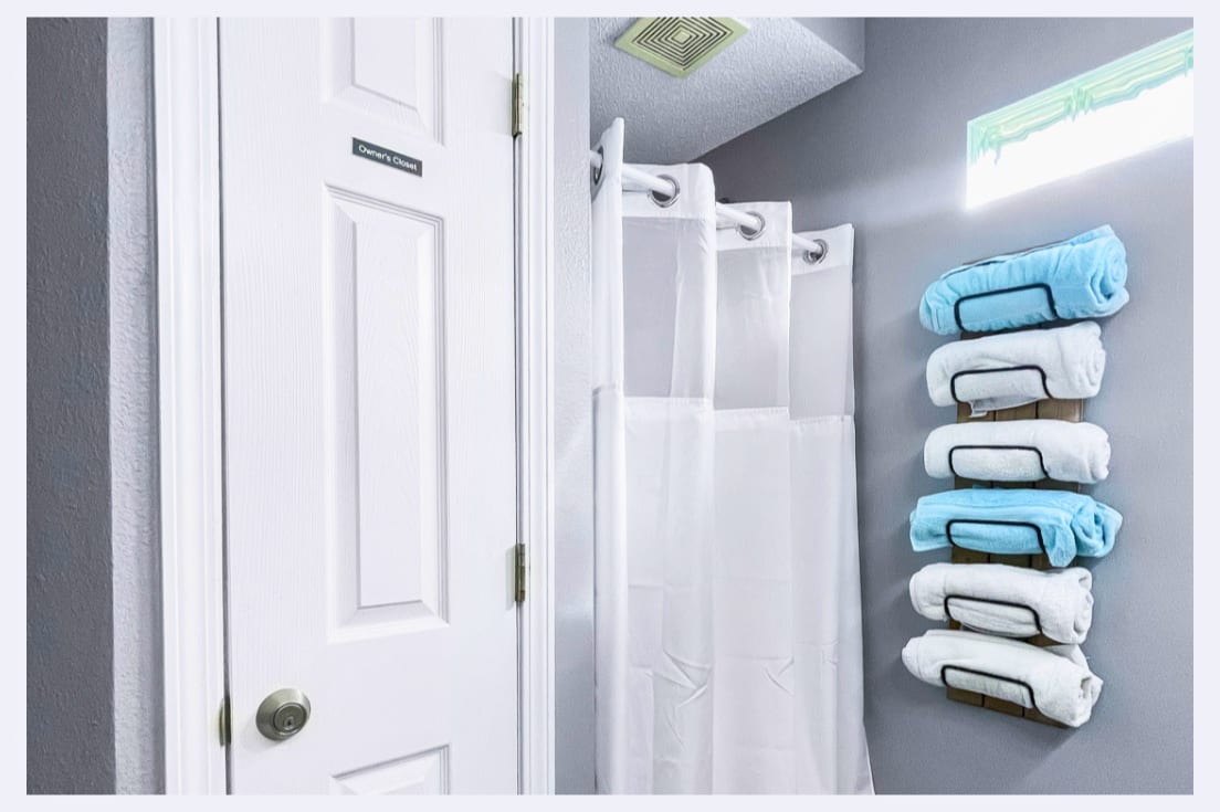 Step into your pristine bathroom where fluffy towels await on stylish wall racks, and fresh linens make every shower feel luxurious.