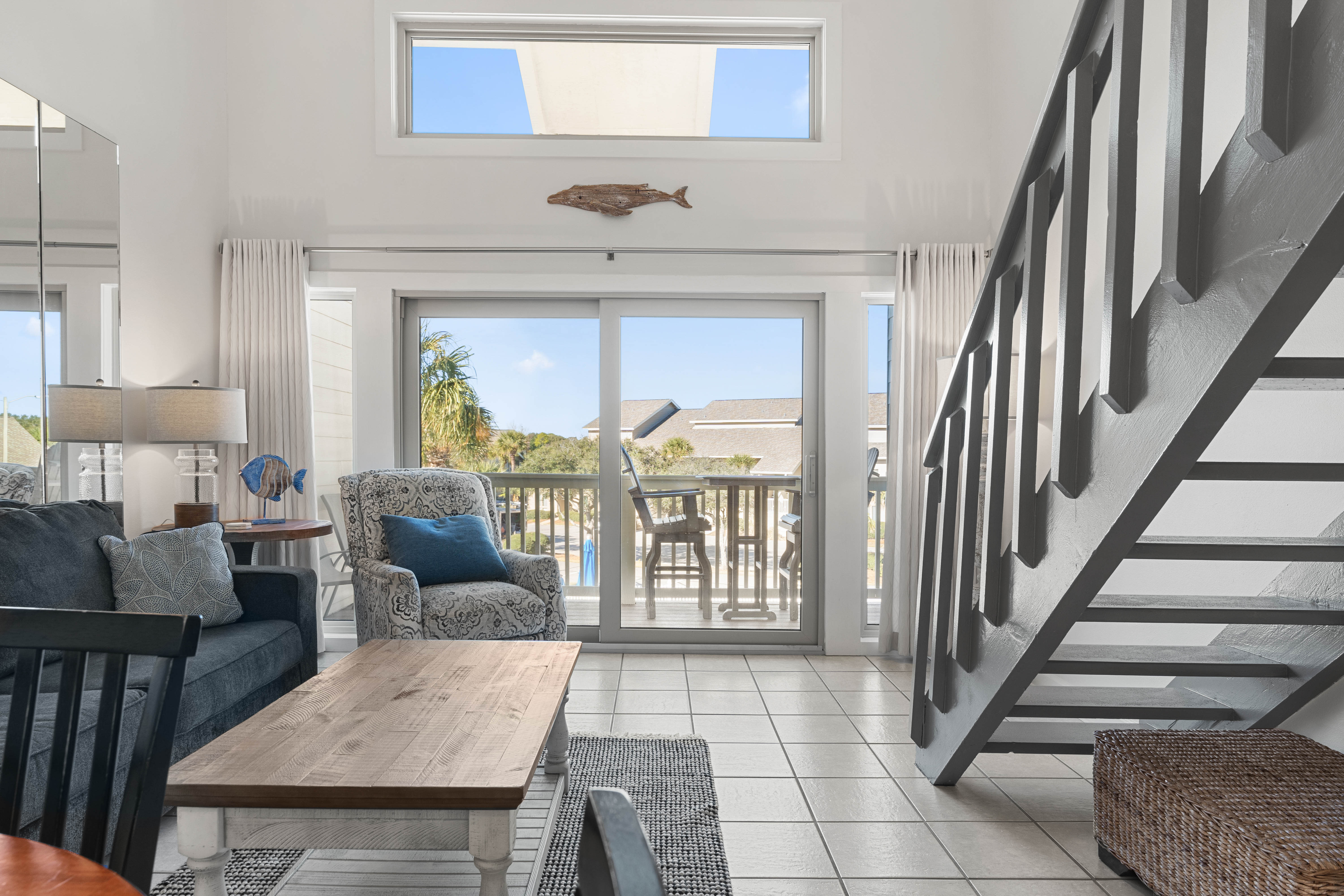Relax in your bright coastal living room with ocean-themed touches and private balcony access.