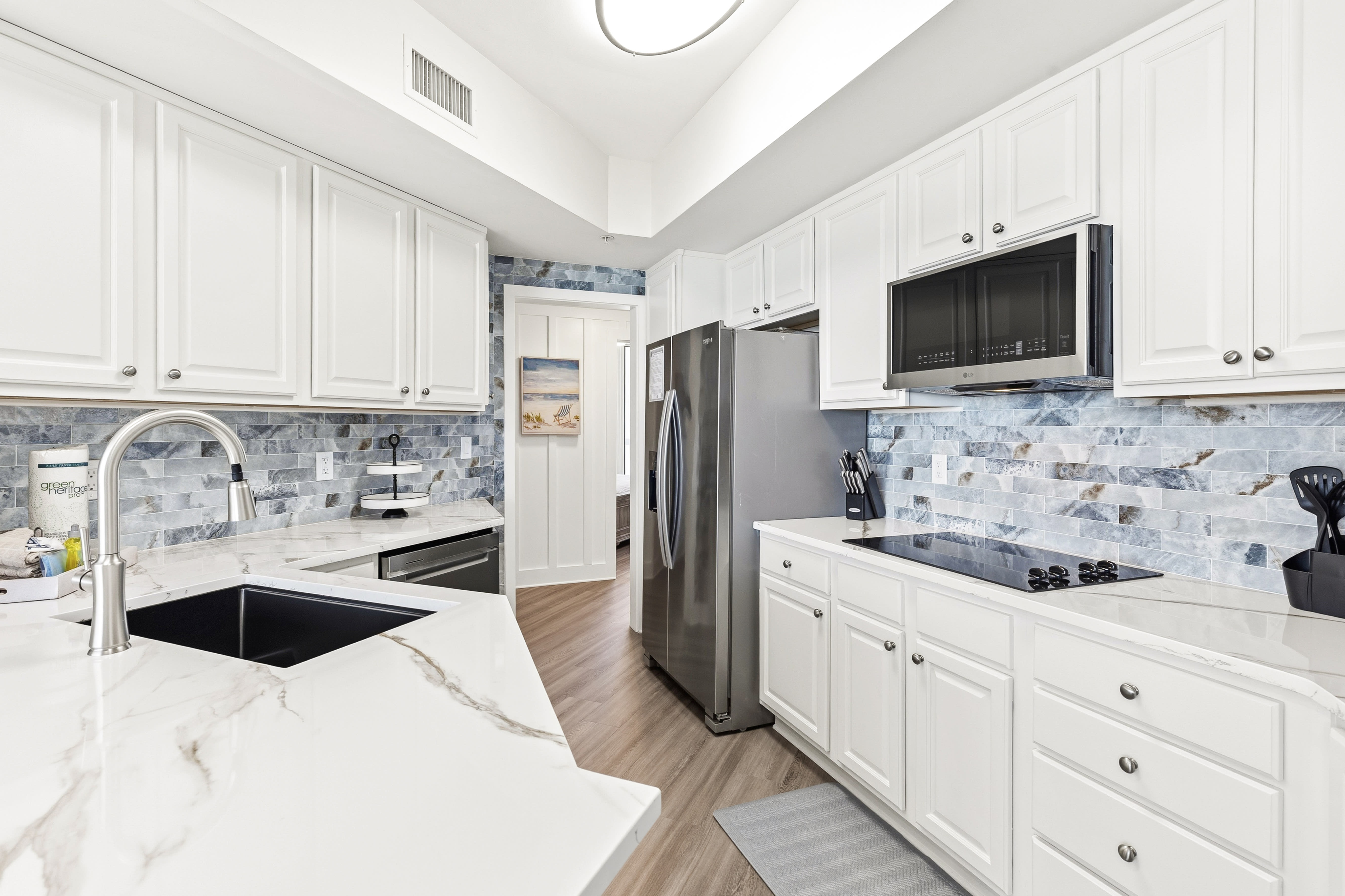 Your fully-equipped kitchen invites culinary adventures with sleek marble counters, stainless appliances, and beautiful coastal-inspired backsplash tiles.