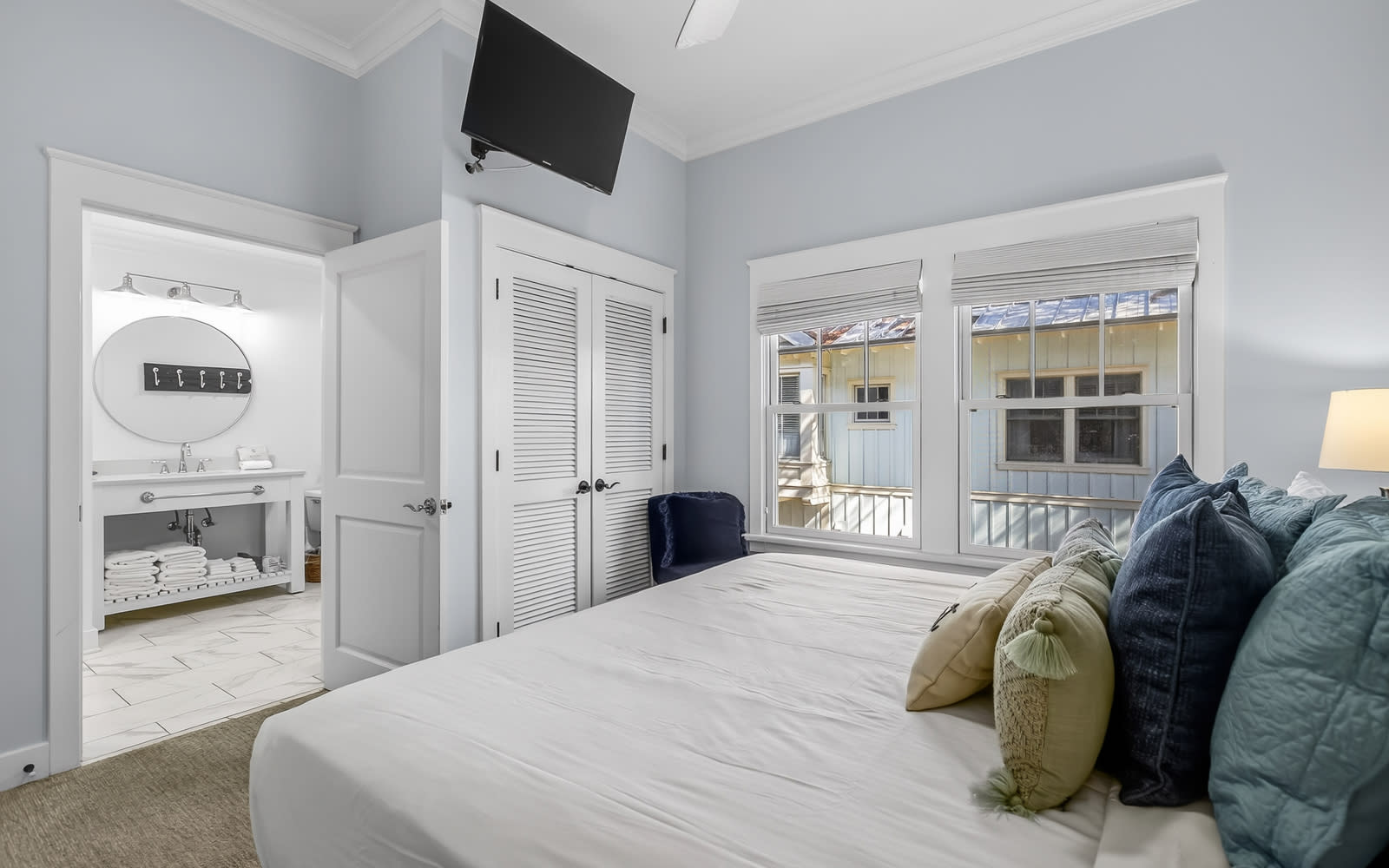 Drift off in this serene bedroom with crisp linens, en-suite bath, and charming windows overlooking peaceful surroundings.