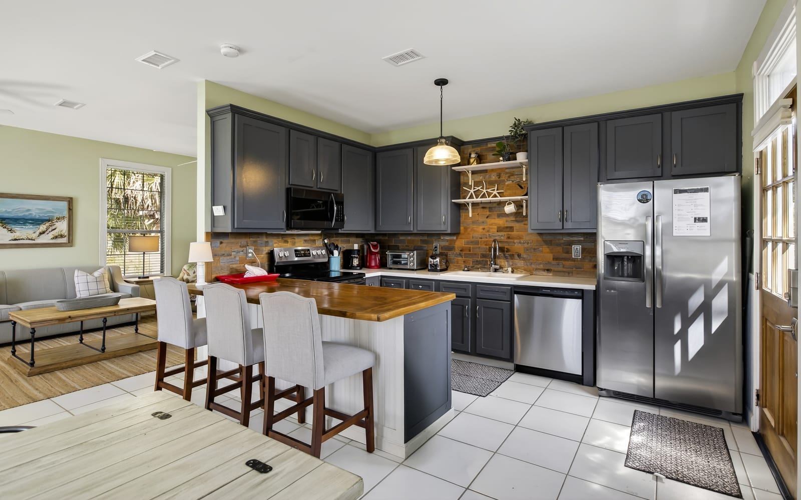 Your spacious kitchen features sleek navy cabinets, gleaming stainless appliances, and a warm brick backsplash, perfect for cooking memorable meals together.