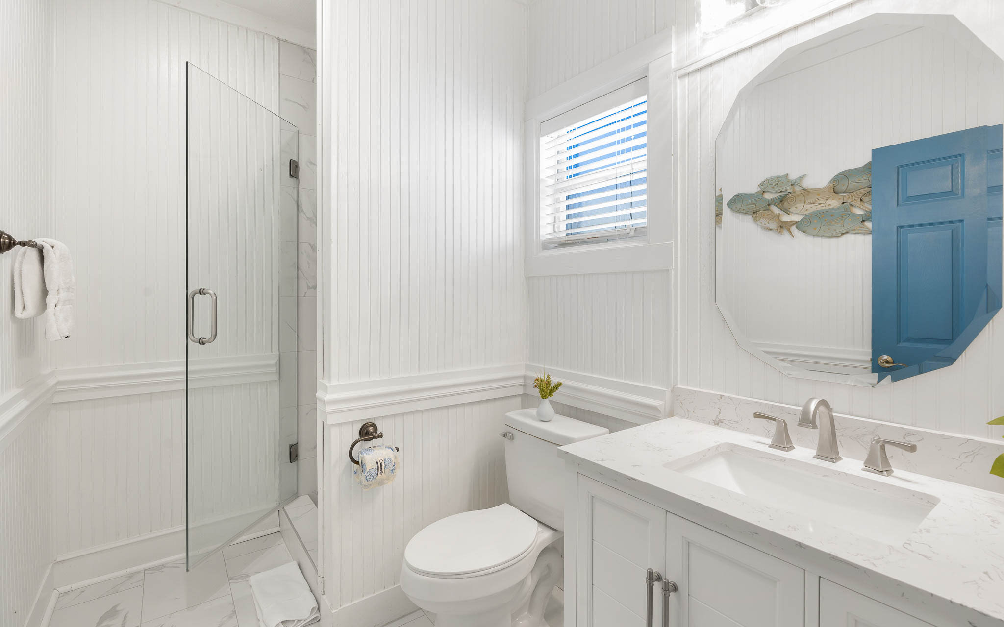 Unwind in your pristine bathroom featuring elegant white marble, a spacious walk-in shower, and charming coastal touches that create a spa-like retreat.