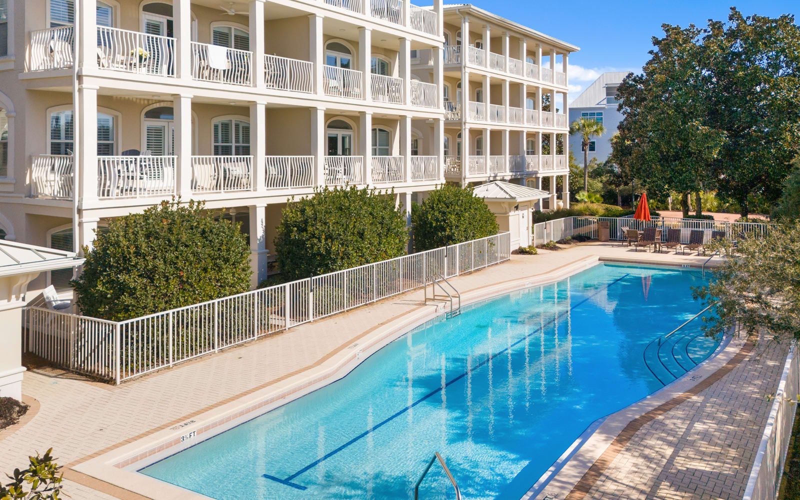 Elegant multi-story vacation property featuring a pristine swimming pool surrounded by lush landscaping and stylish balconies.