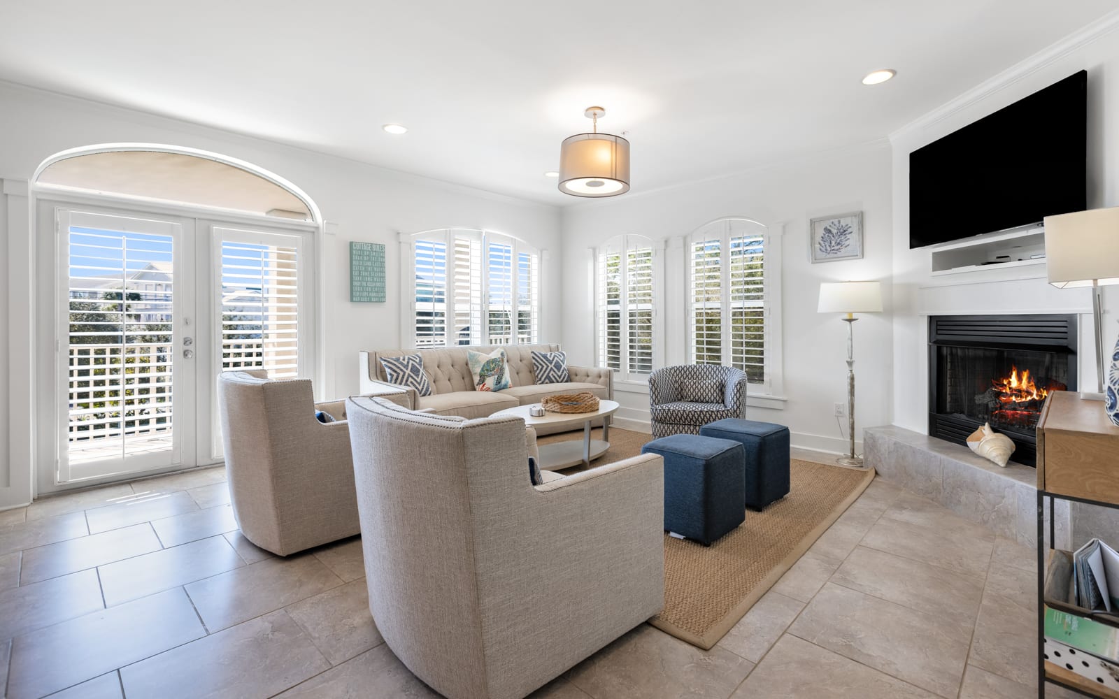 Relax in your bright living room with cozy fireplace, comfortable seating, and peaceful shuttered windows creating the perfect retreat.