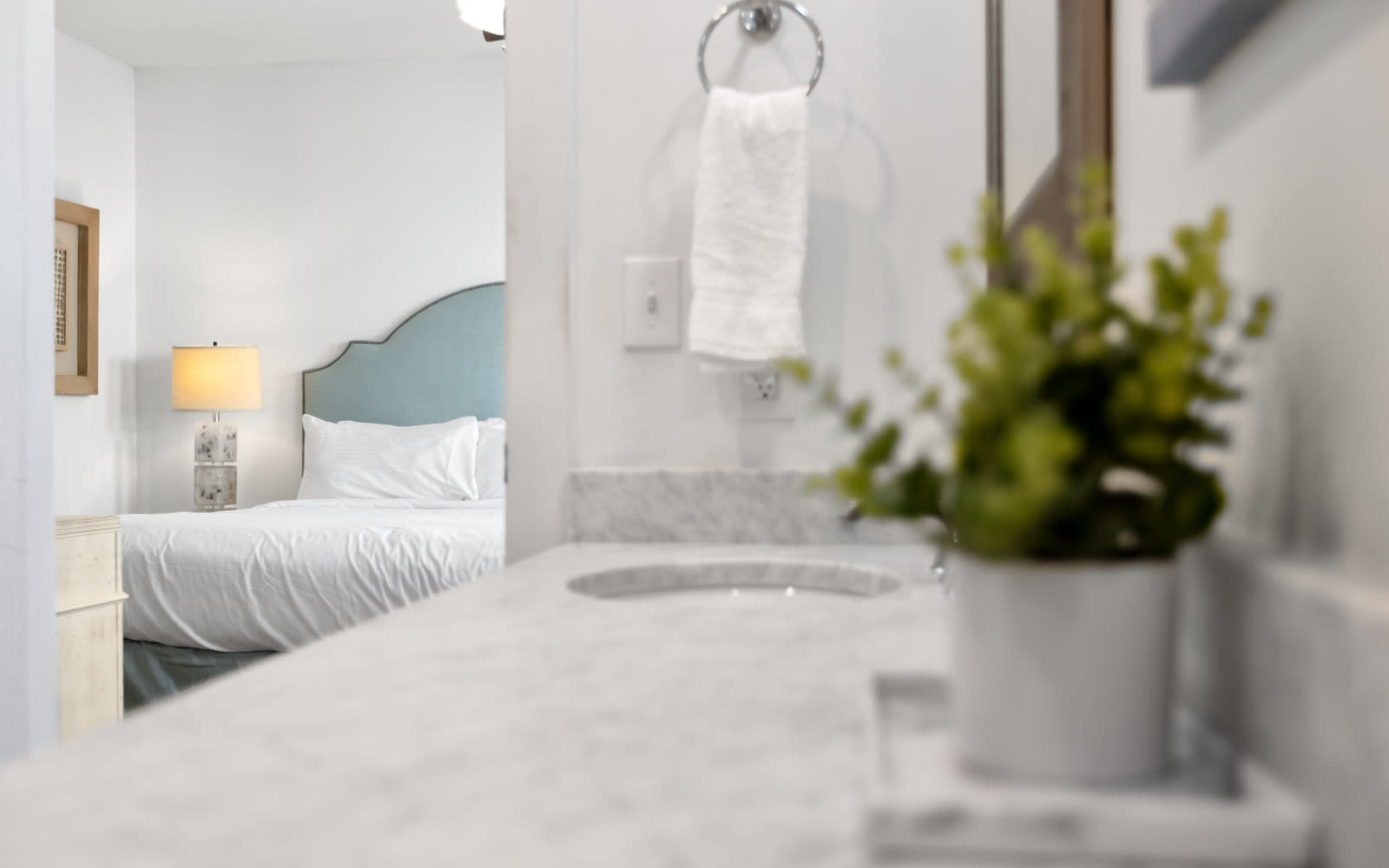 Unwind in your serene bedroom sanctuary where marble textures meet soft linens and fresh greenery creates a peaceful retreat.