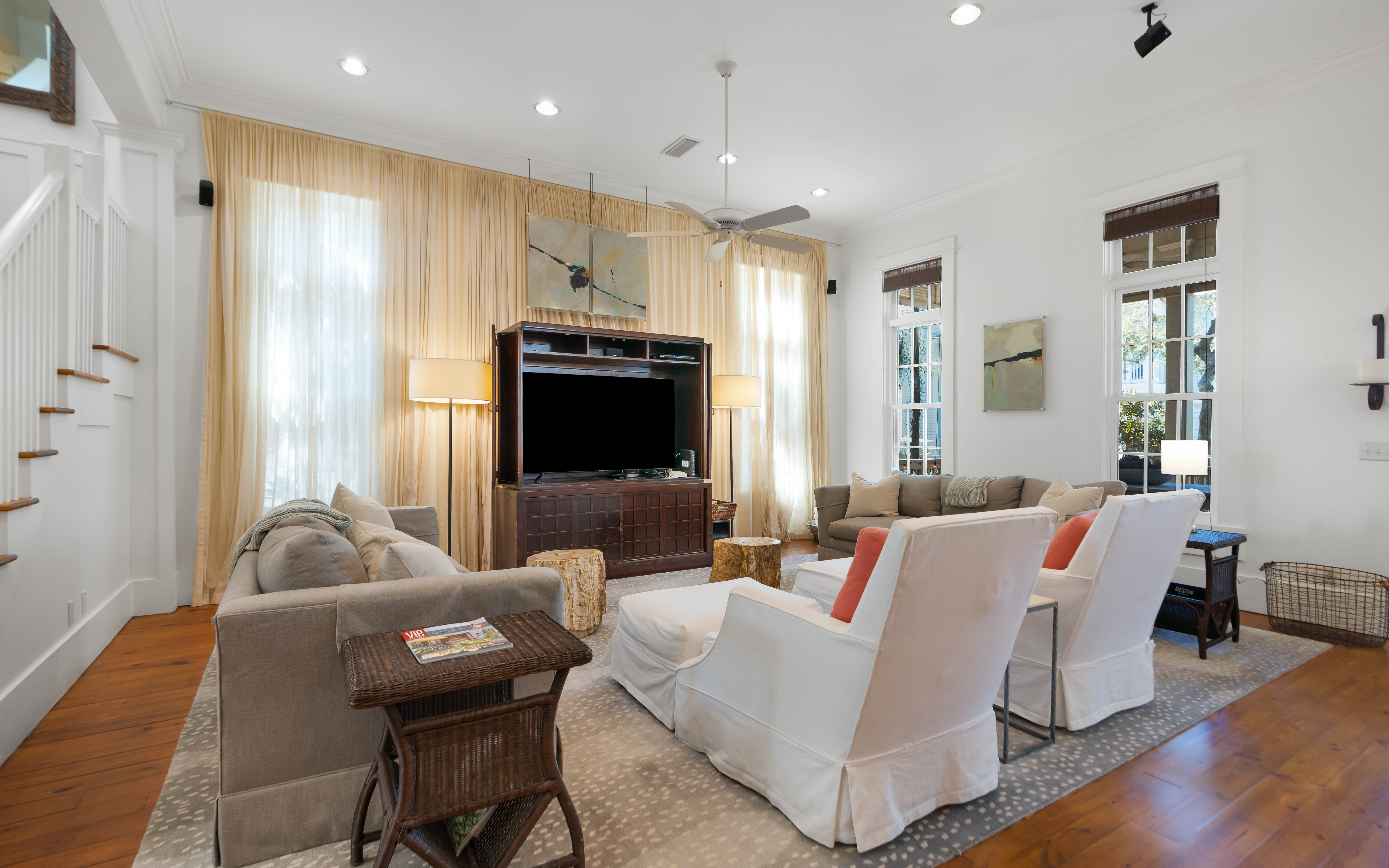 Unwind in your elegantly appointed living room with plush seating, warm hardwood floors, and natural light streaming through golden curtains.