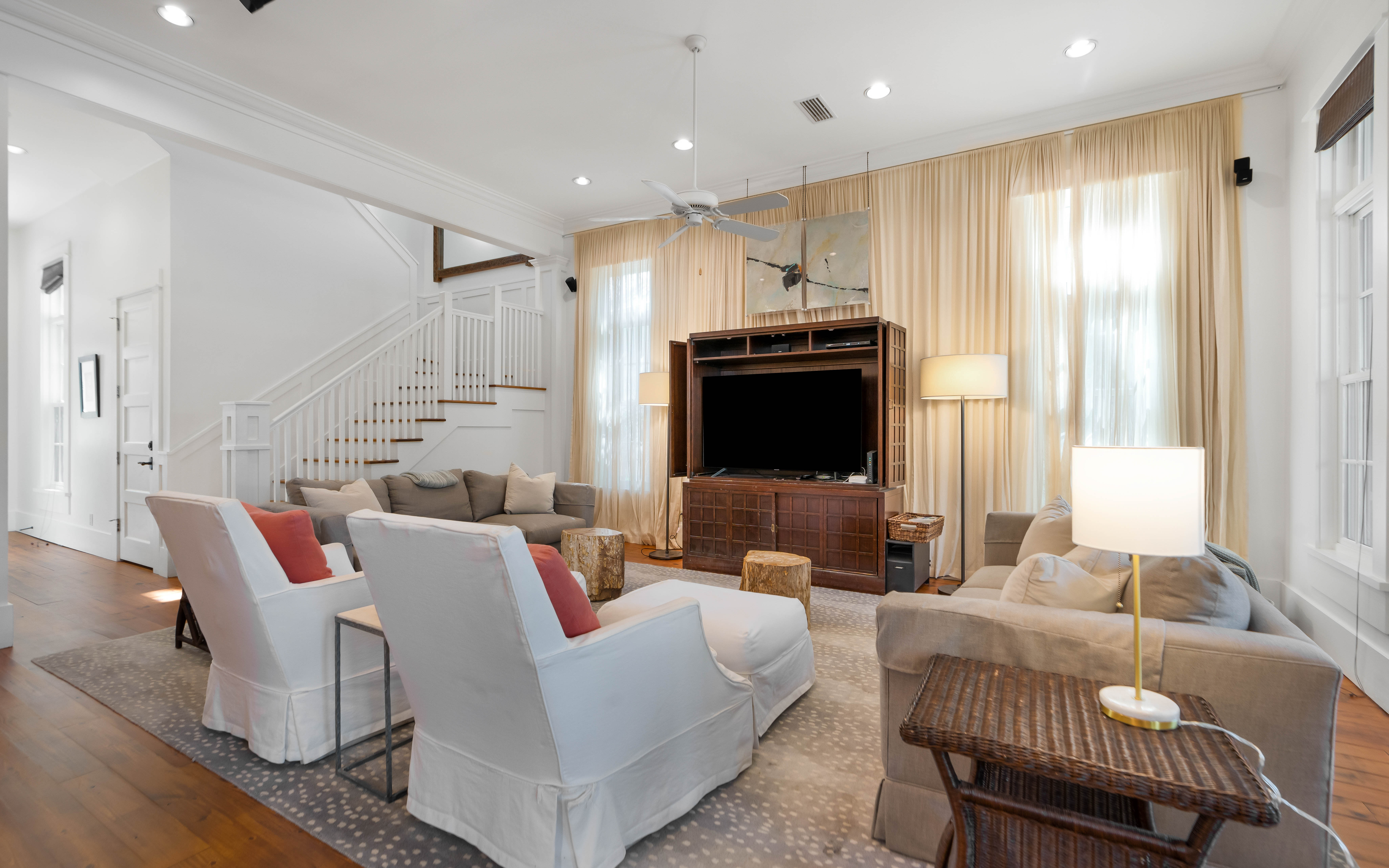 Relax in your elegant living room with plush seating, entertainment center, and warm natural light streaming through floor-to-ceiling windows.